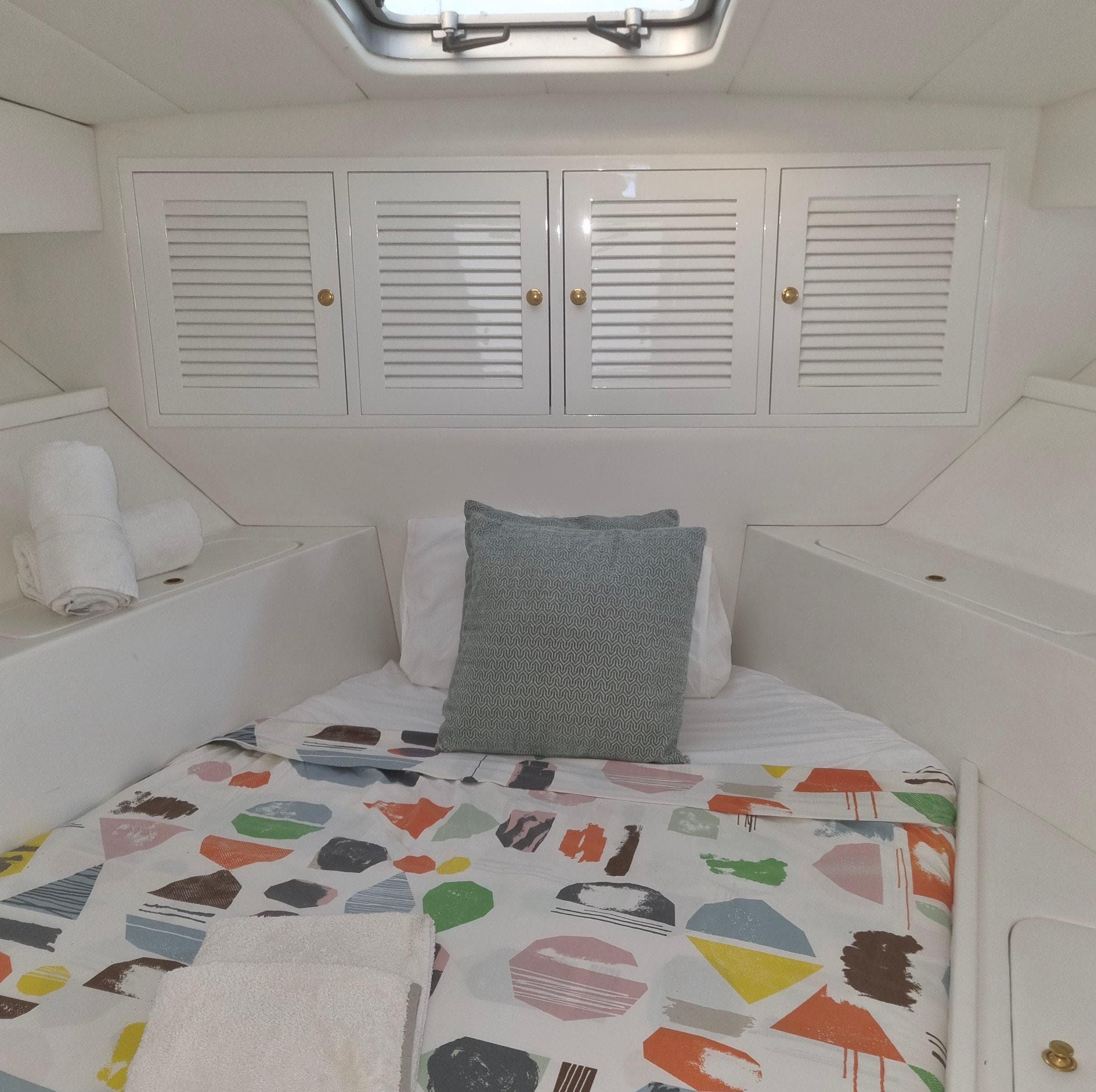 Cozy cabin interior of 1990 Magnum 40 yacht with colorful bedding and white cabinets.