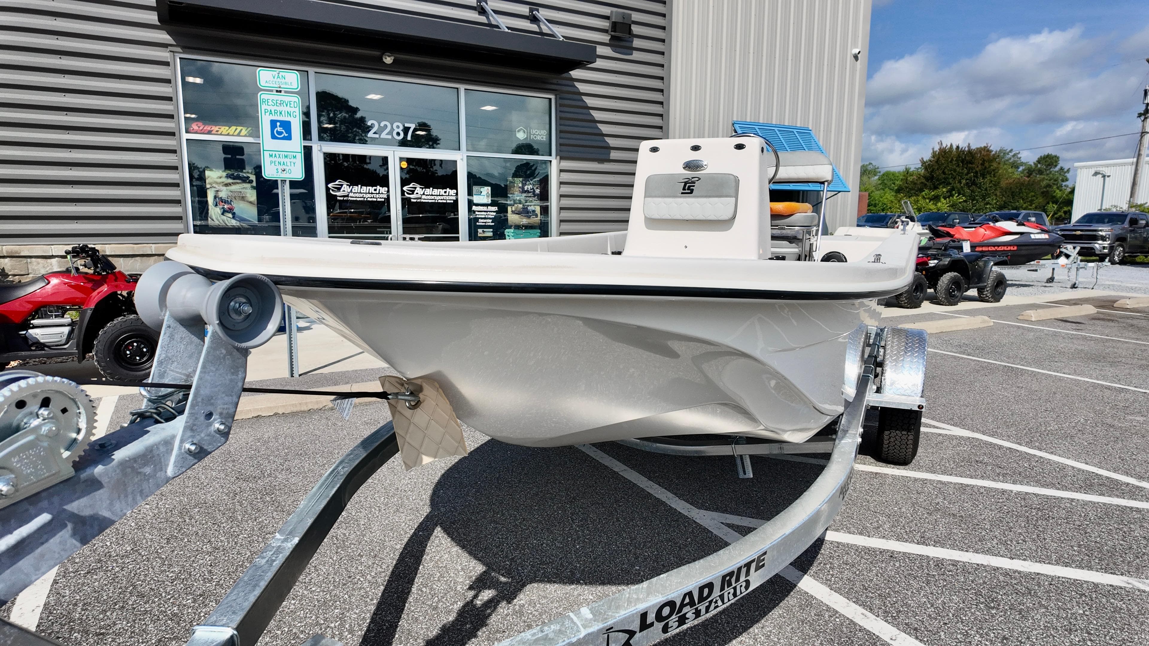 2025 Carolina Skiff E18 JVX CC boat on trailer outside dealership.