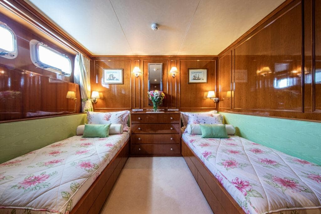Luxurious 1982 Feadship Classic yacht cabin with twin beds and elegant wood paneling.