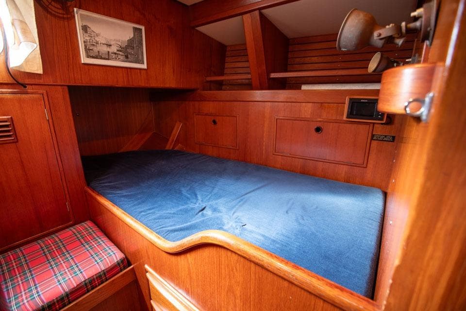 Cozy wooden cabin interior of 1983 Nautor Swan 65 yacht with blue bedding.