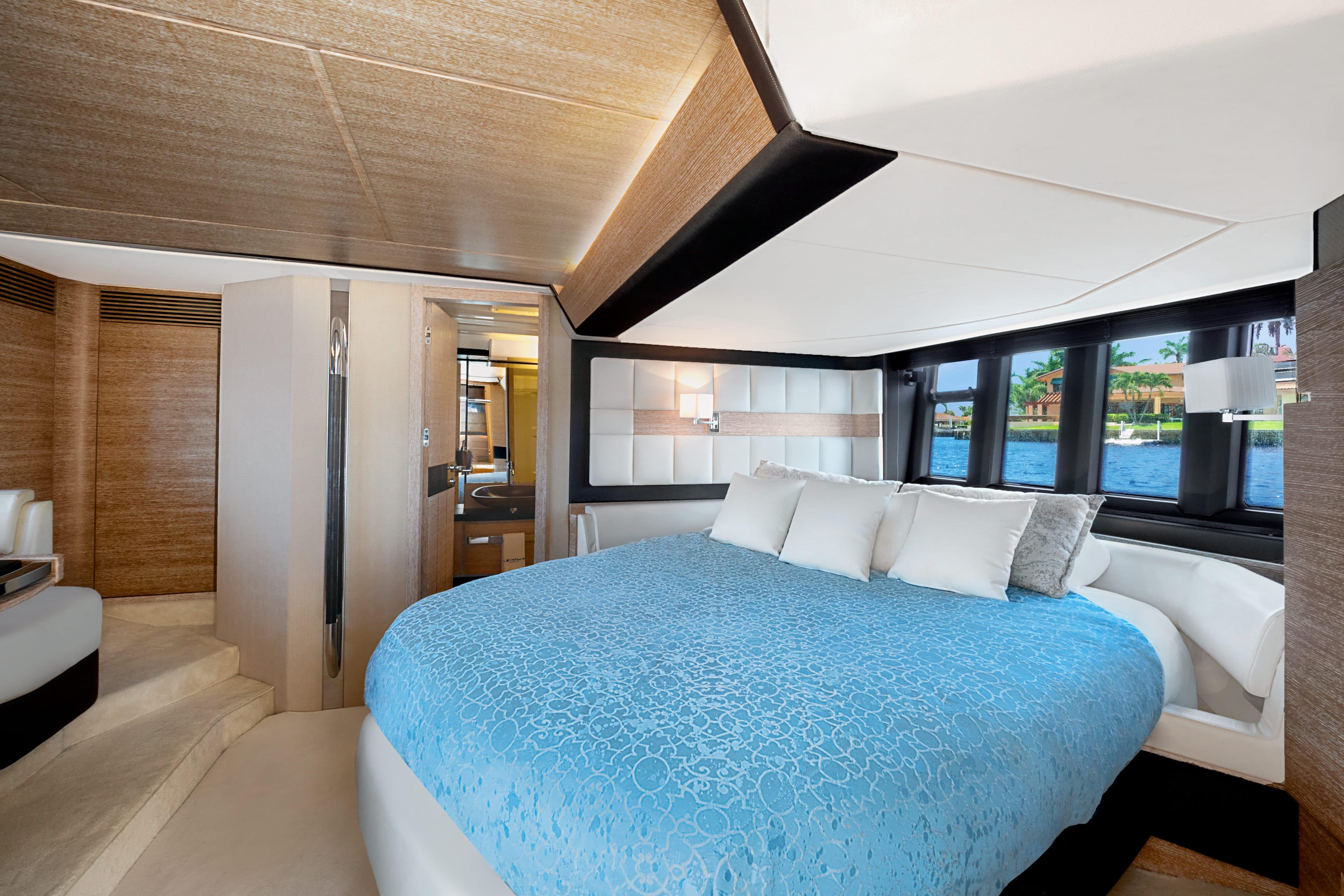 Luxurious bedroom interior of 2013 Azimut 64 yacht with blue bedding and scenic window view.