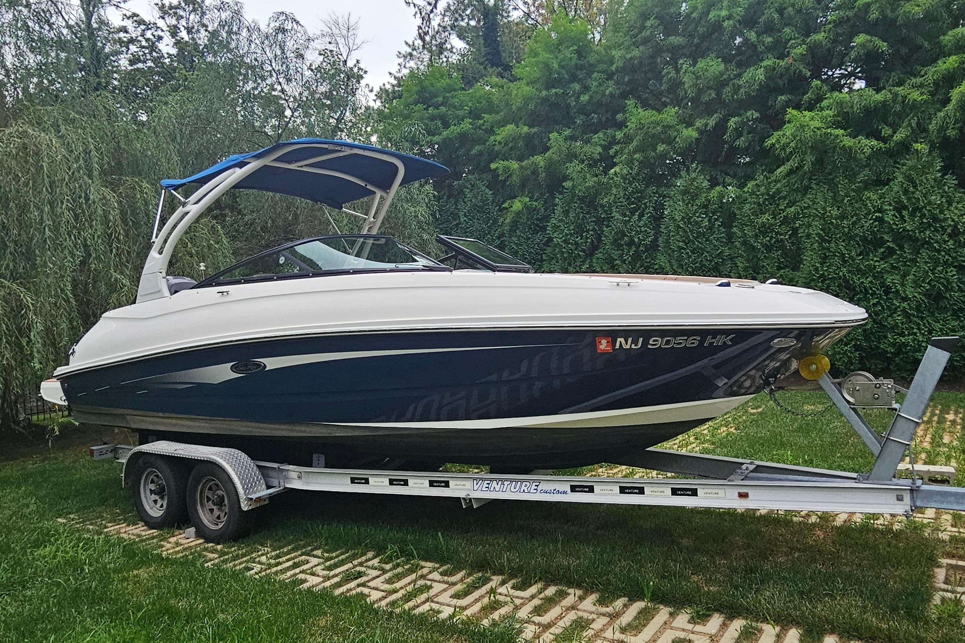 2017 Sea Ray SDX 240 Outboard boat on trailer, surrounded by lush greenery.