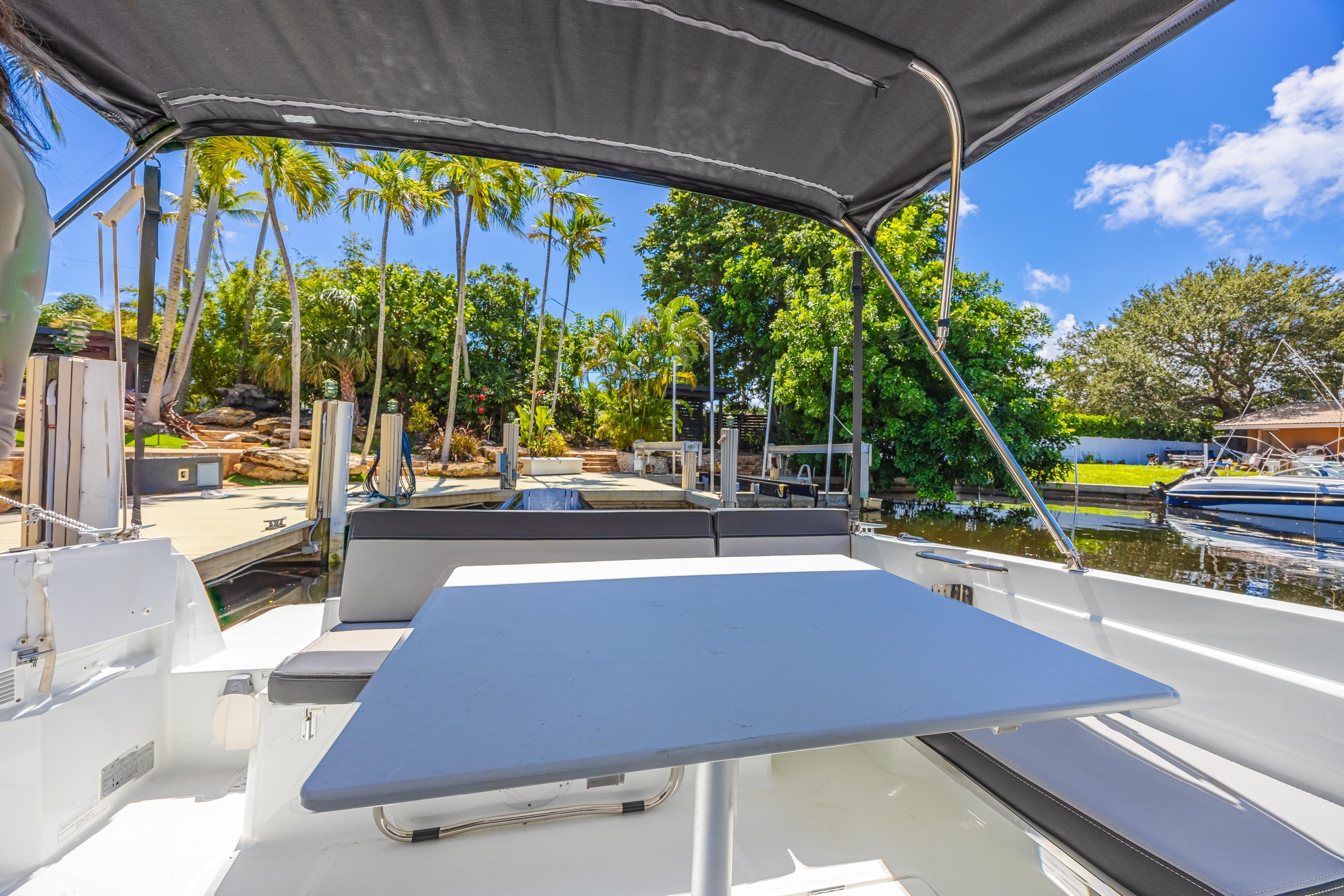 2022 Jeanneau NC 795 Series 2 boat with canopy, docked near lush greenery and palm trees.