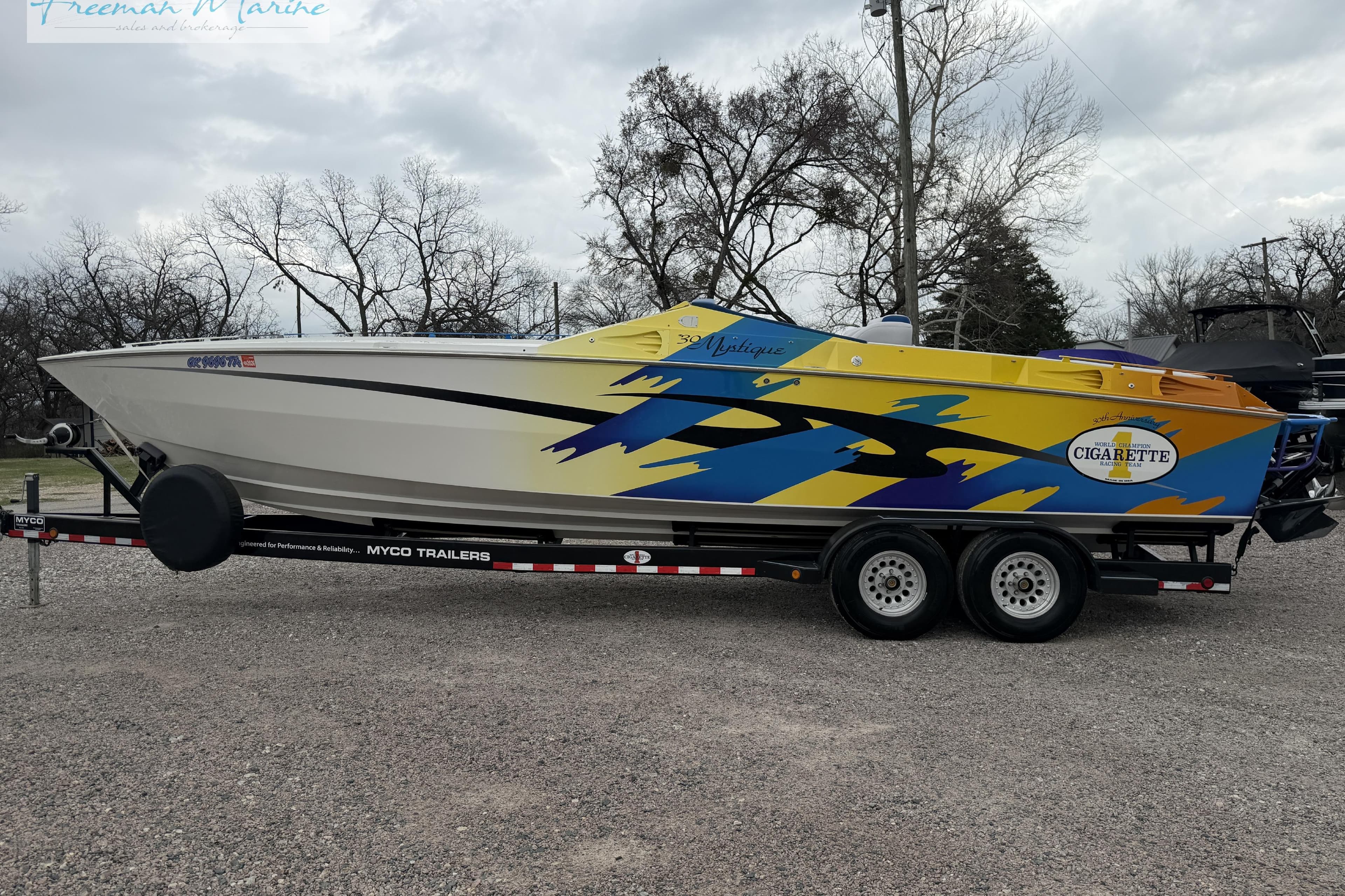 2000 Cigarette 30' Mystique speedboat on trailer, vibrant yellow and blue design.