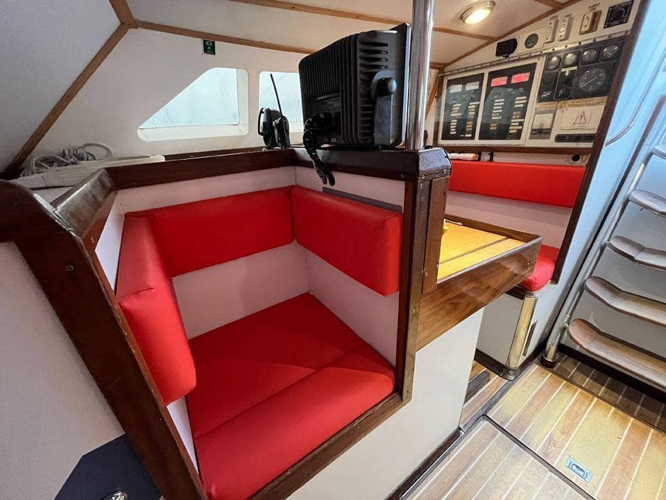 Red seating area in 1992 Devonport Challenge 67 yacht with navigation equipment.