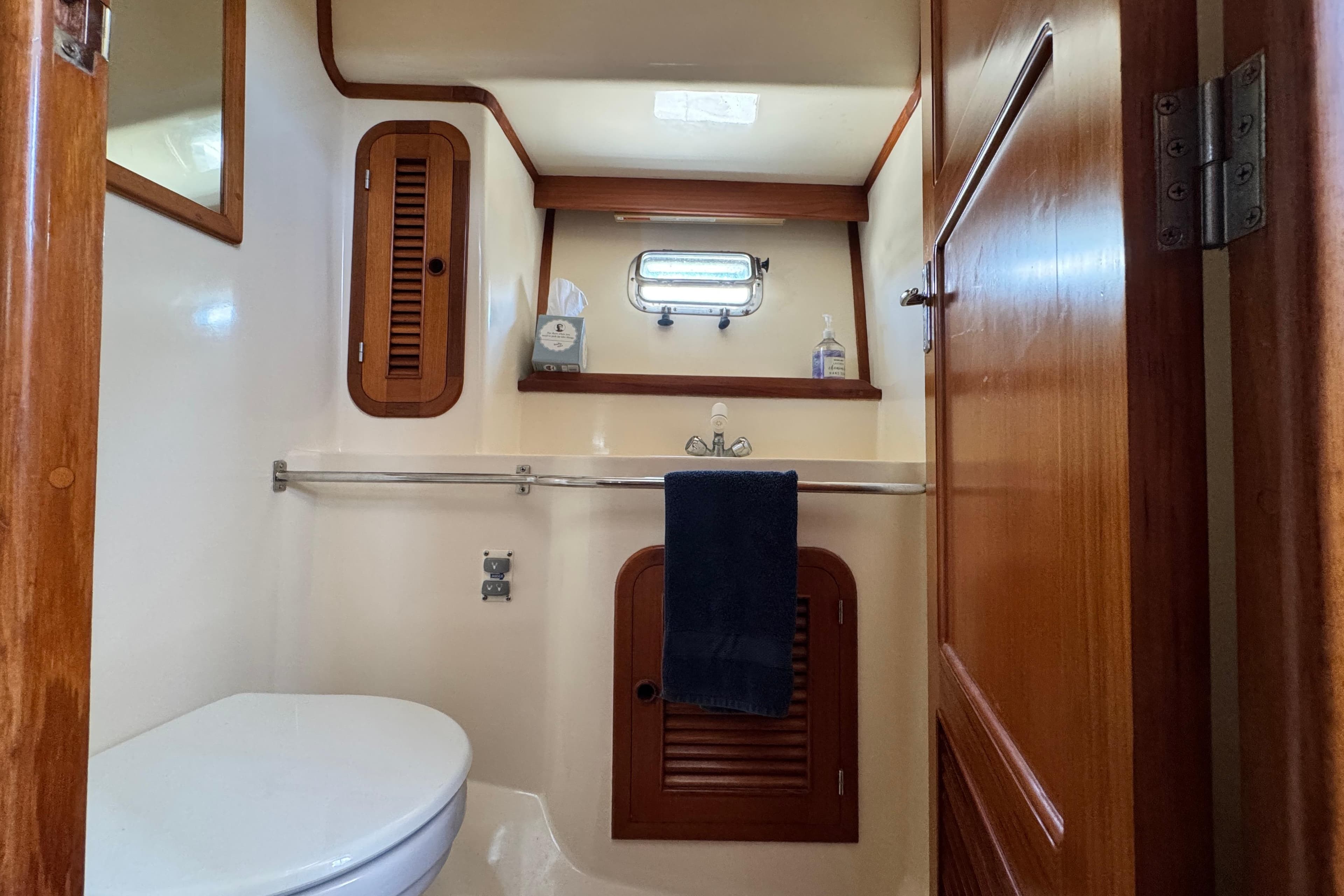 1999 Heritage East Sundeck 36 yacht bathroom with wooden cabinetry and porthole window.