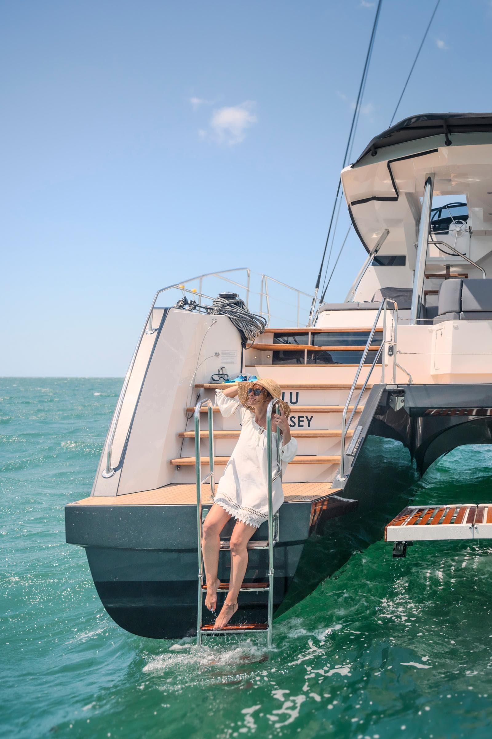Woman relaxing on a 2025 Privilege Signature 650 yacht ladder in the ocean.