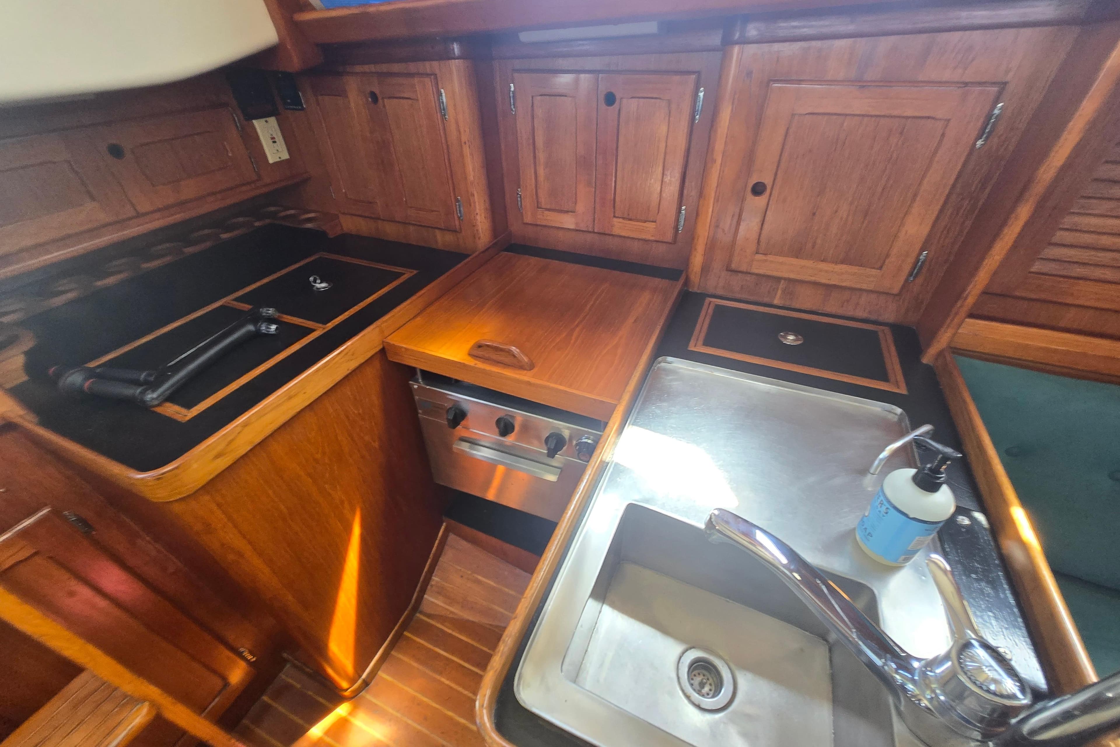 1983 Bristol 38.8 yacht kitchen with wooden cabinets, stove, and sink.