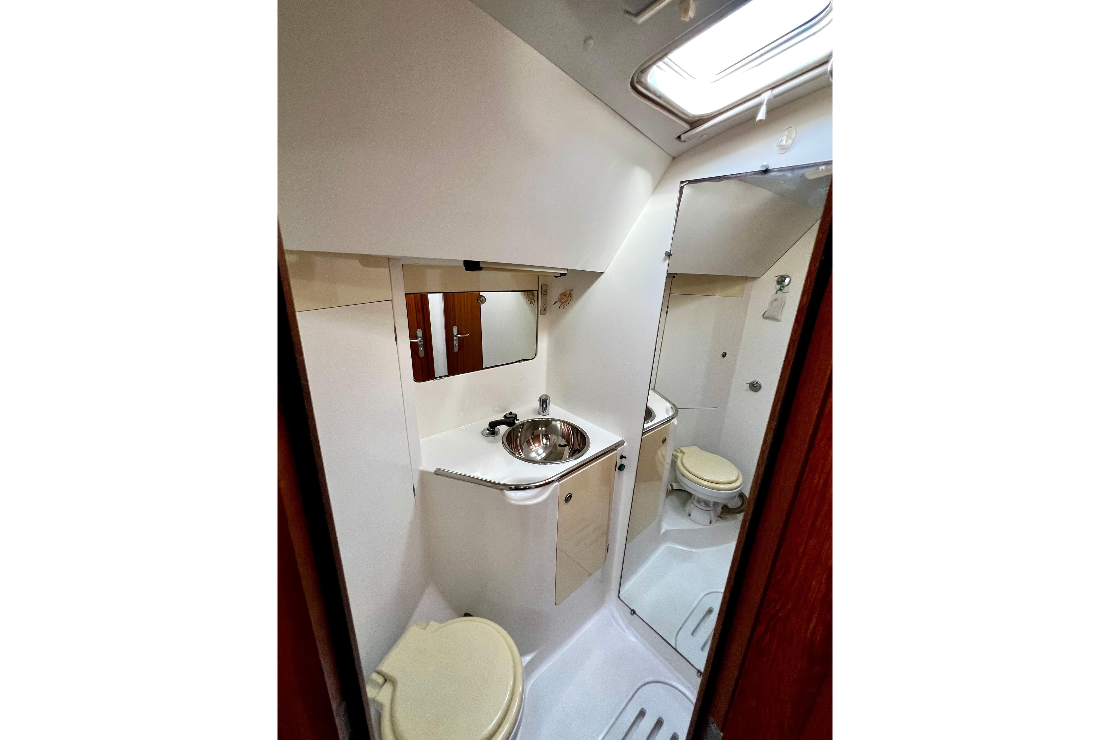 Compact bathroom in 1995 Jeanneau Sun Odyssey 45.1 yacht with sink and toilet.
