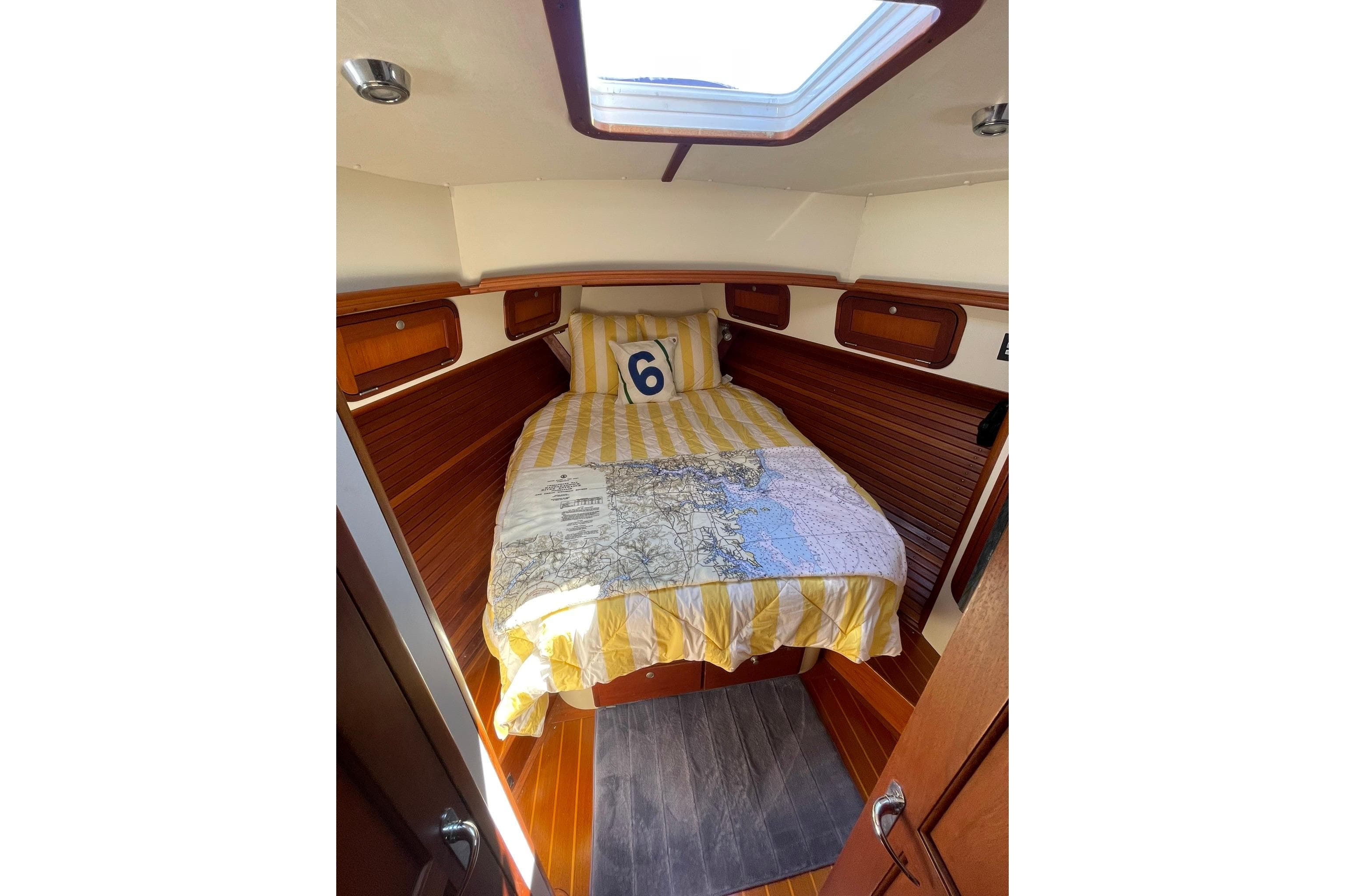 Cozy cabin interior of 1999 Legacy Yachts 40 Sedan with skylight and striped bedding.