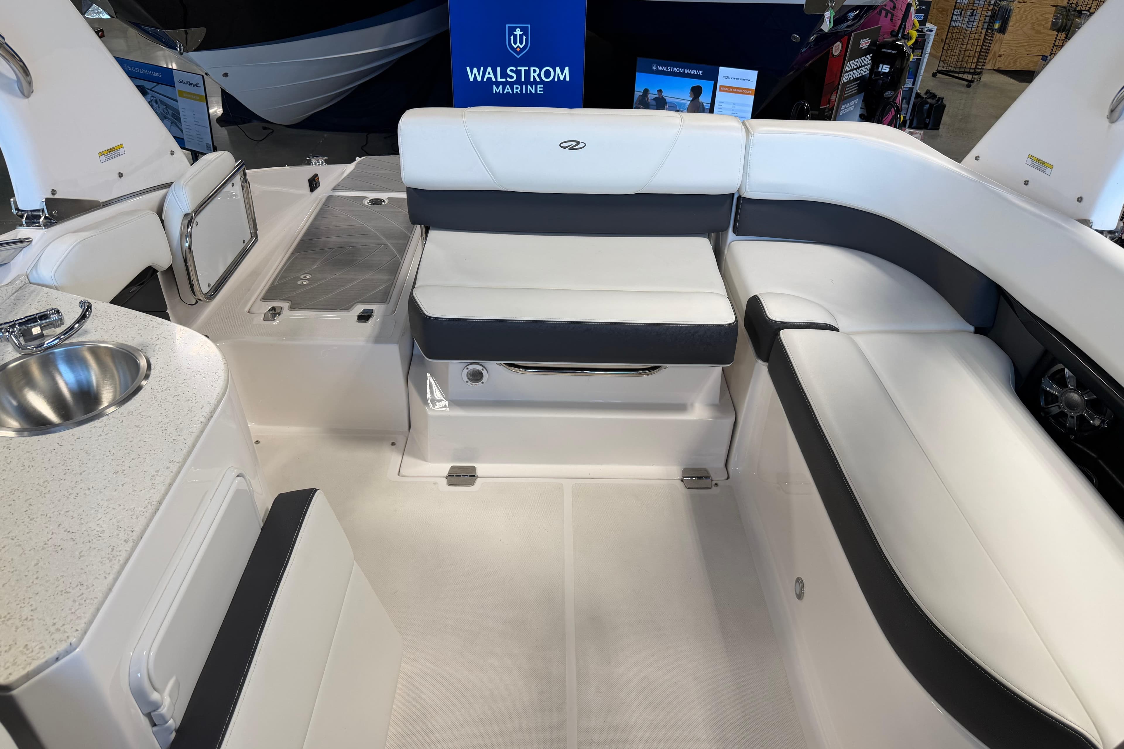 Interior of a 2016 Regal 2550 Cuddy boat with white seating and a small sink.