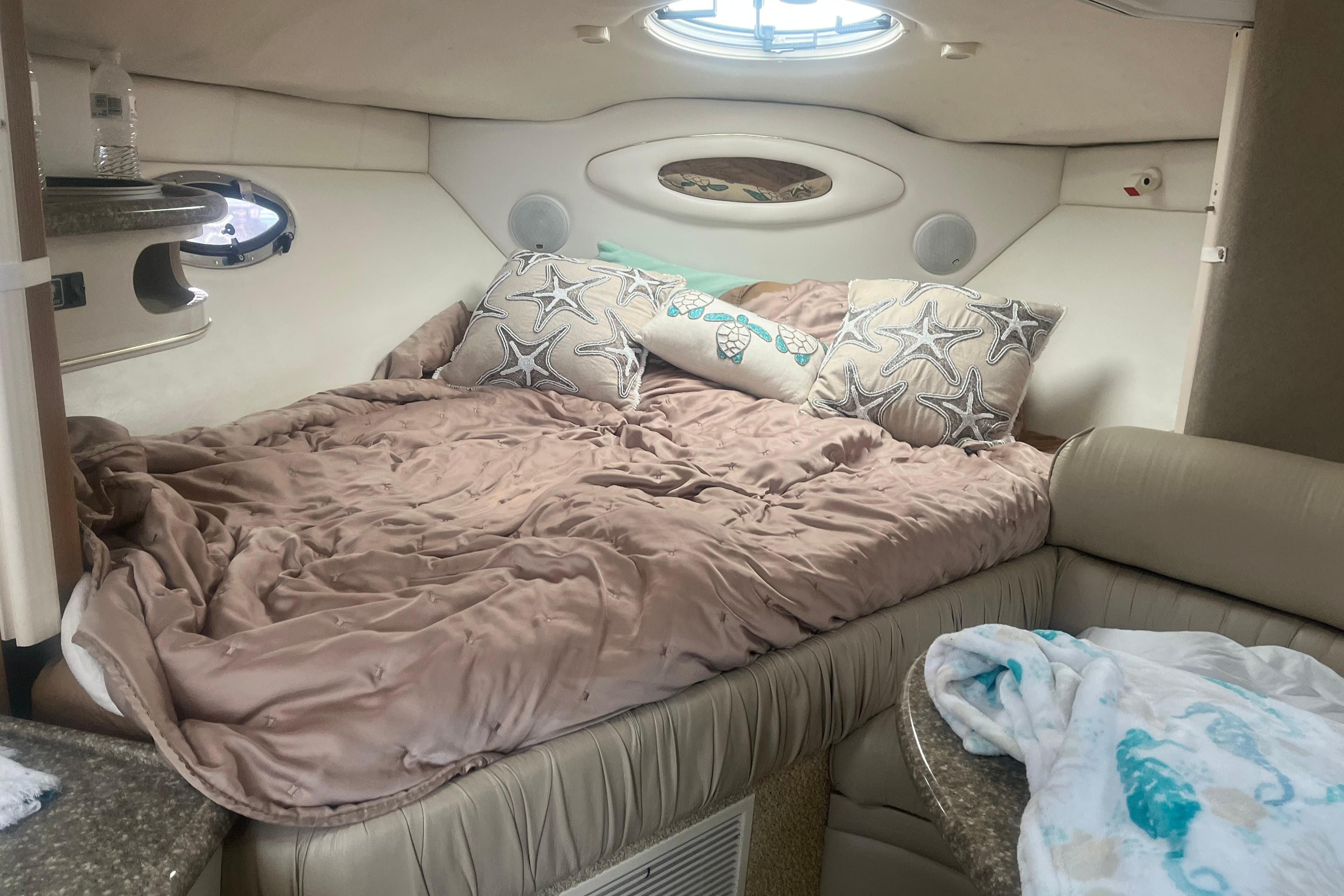 Cozy cabin interior of 1998 Maxum 3000SCR with plush bedding and decorative pillows.