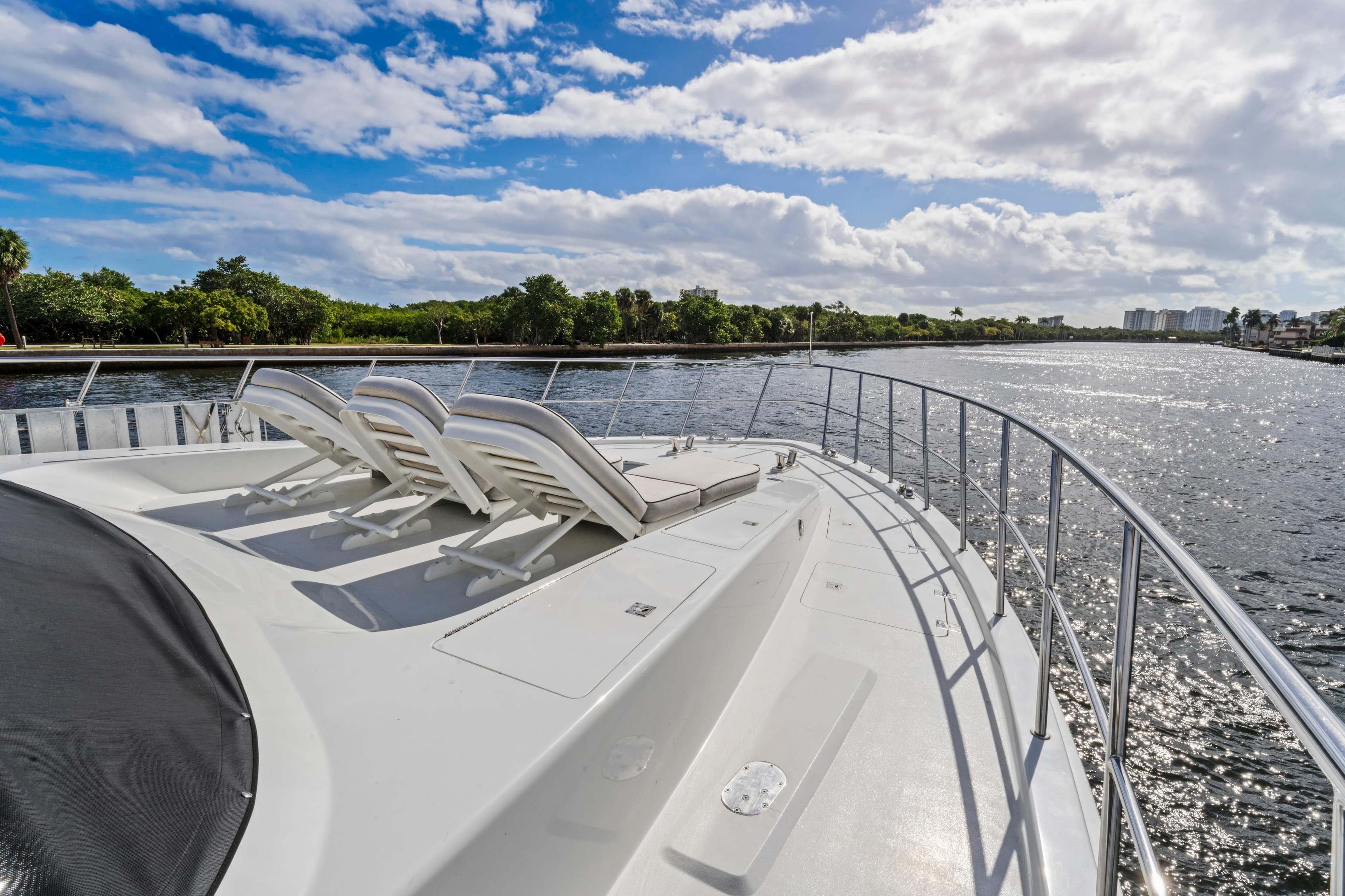 Luxury 2006 Cheoy Lee 84 Bravo yacht with sun loungers on deck, cruising a scenic waterway.