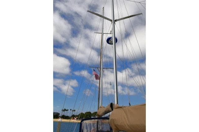 Mason 63 sailboat mast with American flag, clear sky, and palm trees in the background.