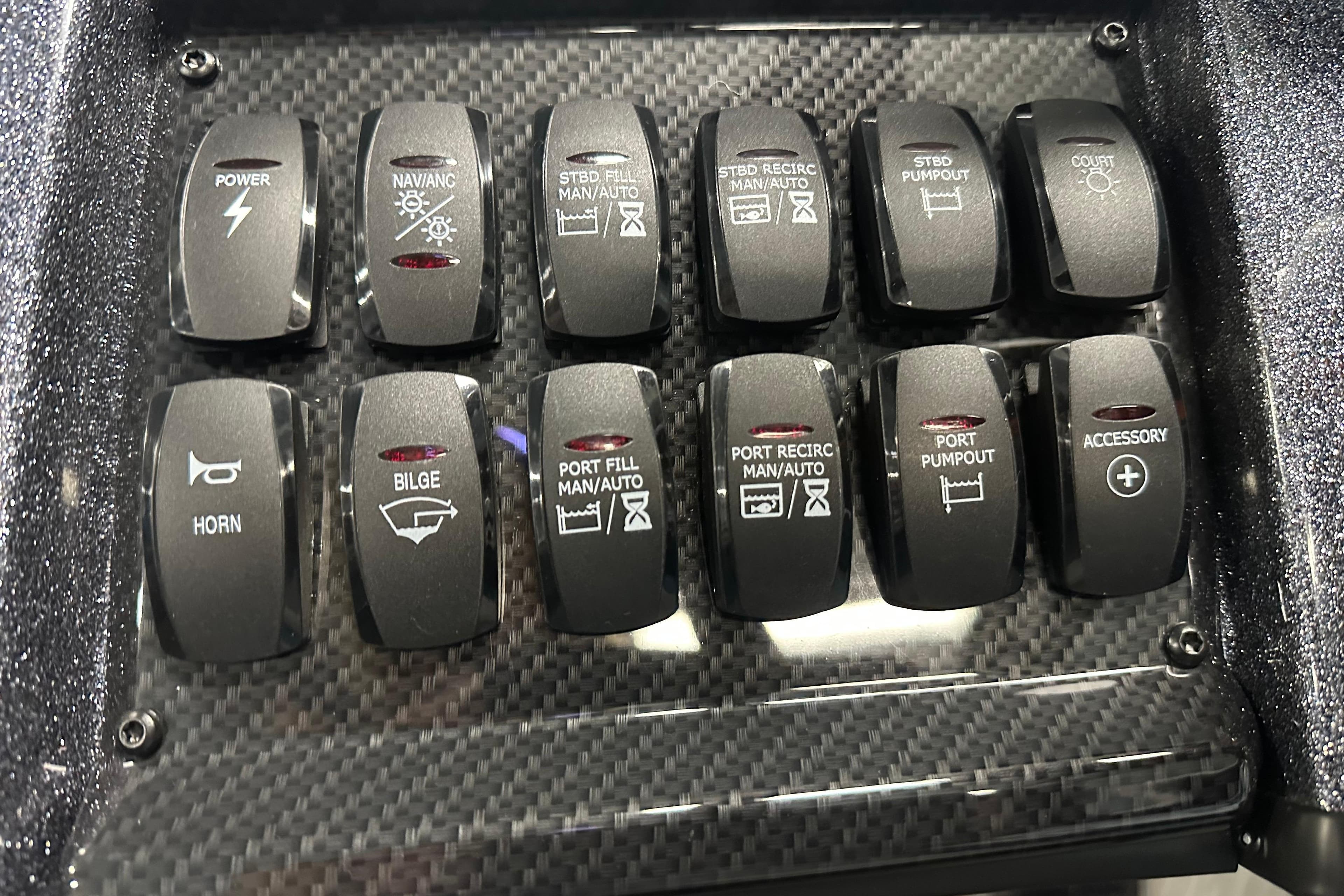 Control panel of a 2026 Triton 20XP boat with various switches on carbon fiber.