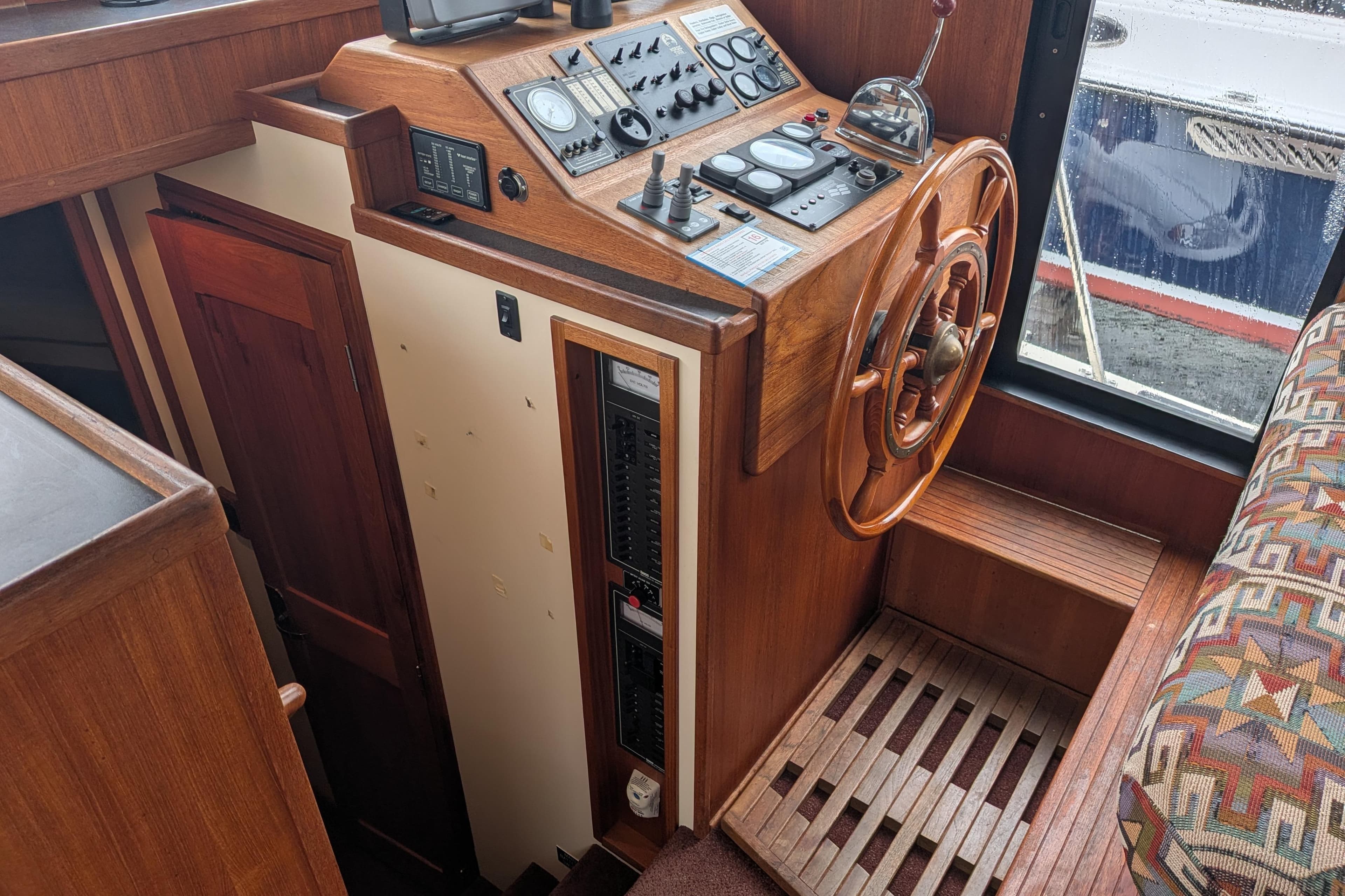 Wooden helm station of a 2000 Nordic Tug 37, featuring classic controls and steering wheel.