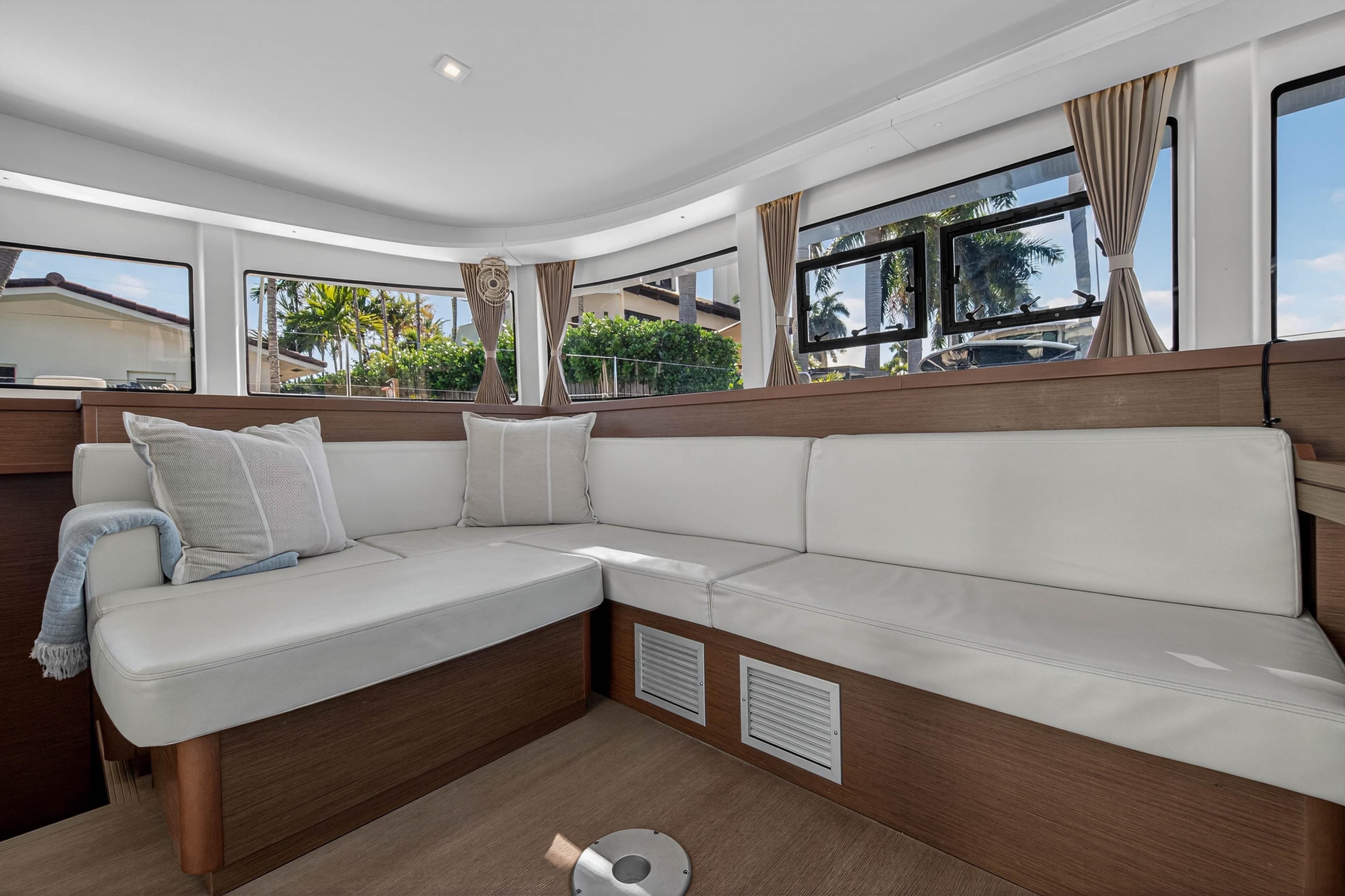 Luxurious interior of 2019 Lagoon 42 catamaran with white seating and large windows.