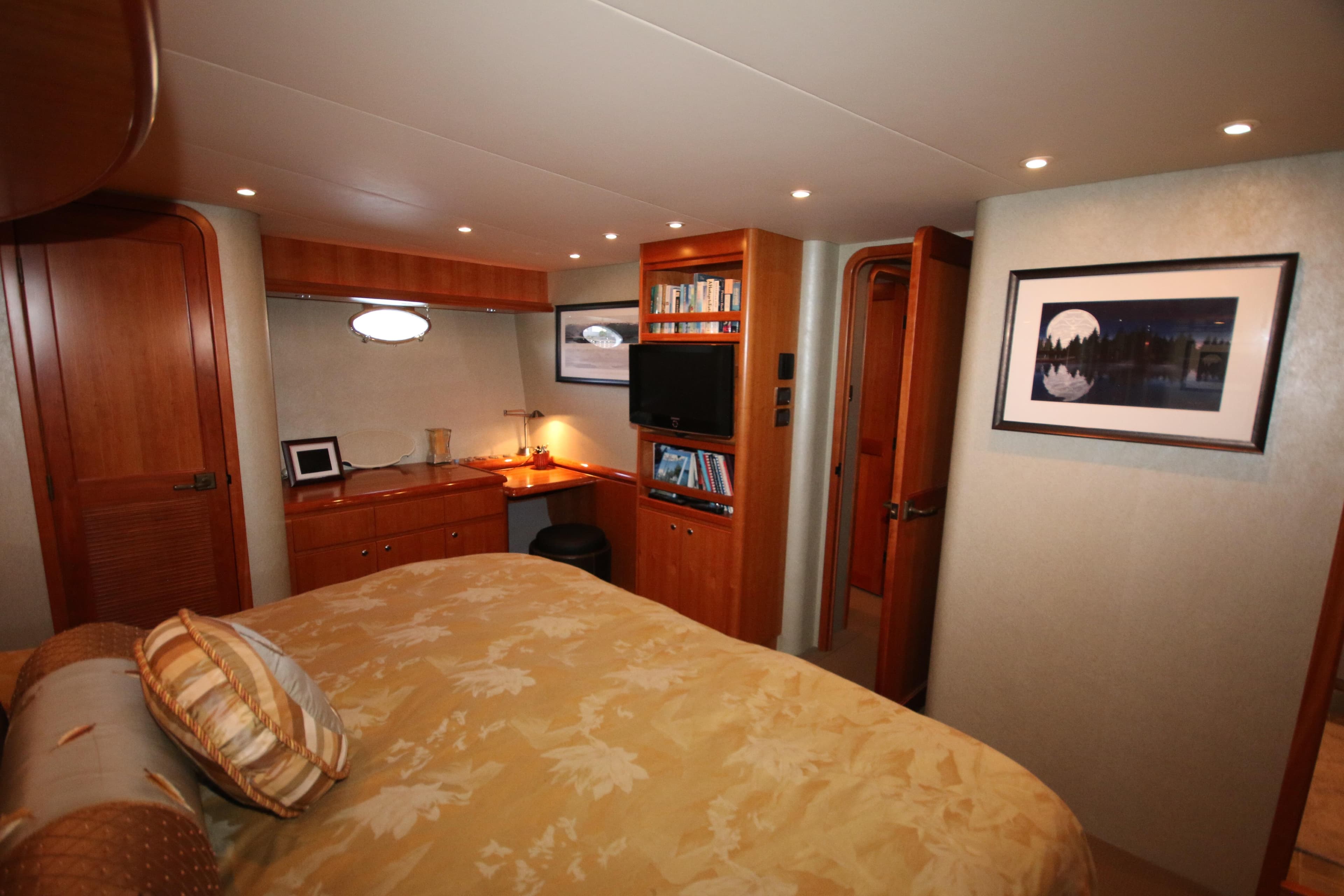 Luxurious bedroom interior of 2004 West Bay 68 Sonship Pilothouse yacht with wood accents.
