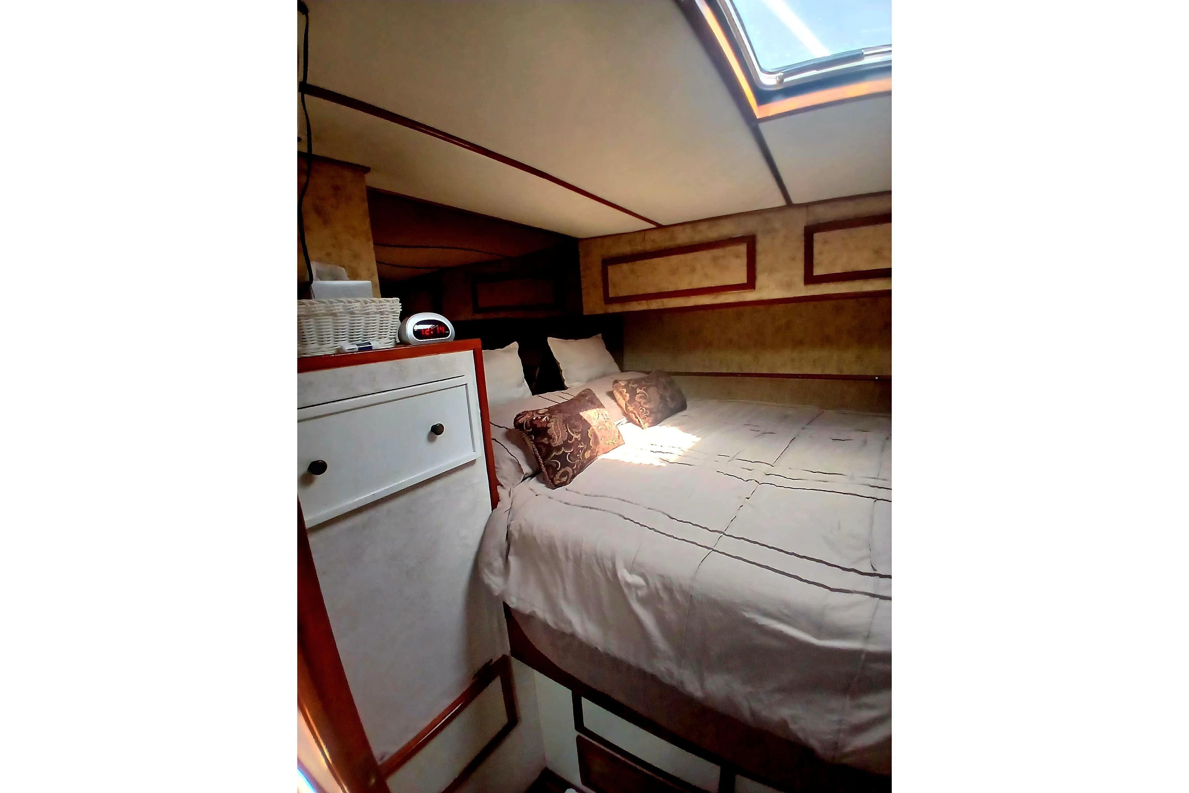 Cozy bedroom interior of 1976 Viking 40 Sedan Diesel boat with skylight and elegant decor.