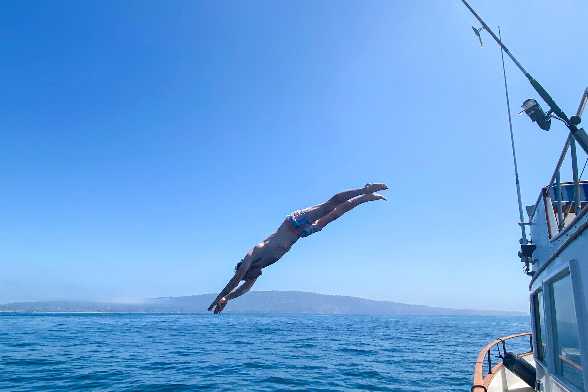 Man diving off 1973 Grand Banks 32 Sedan into the ocean on a sunny day.