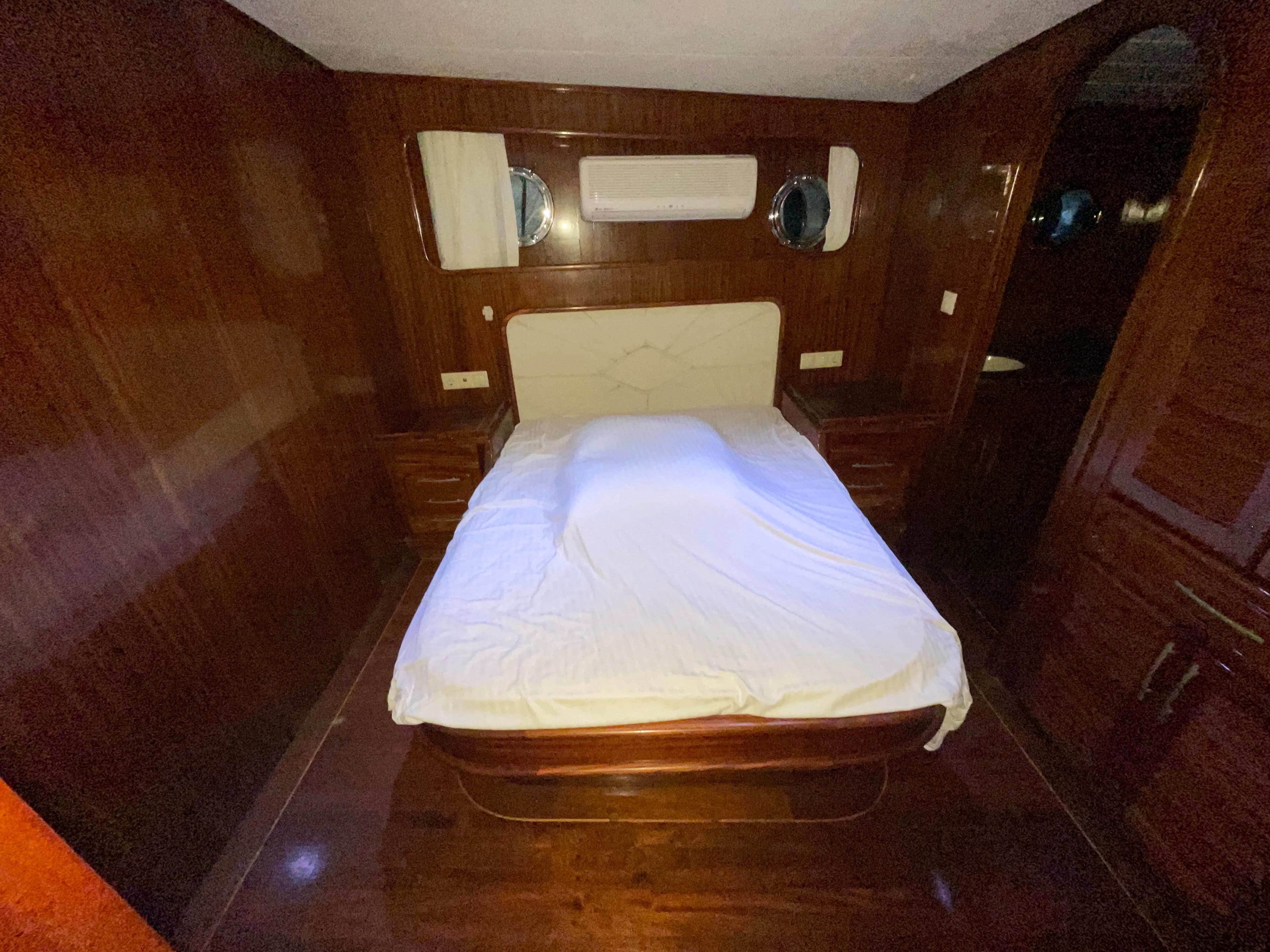 Luxurious wooden cabin interior of 2012 Custom Gulet Motorsailer with bed and portholes.