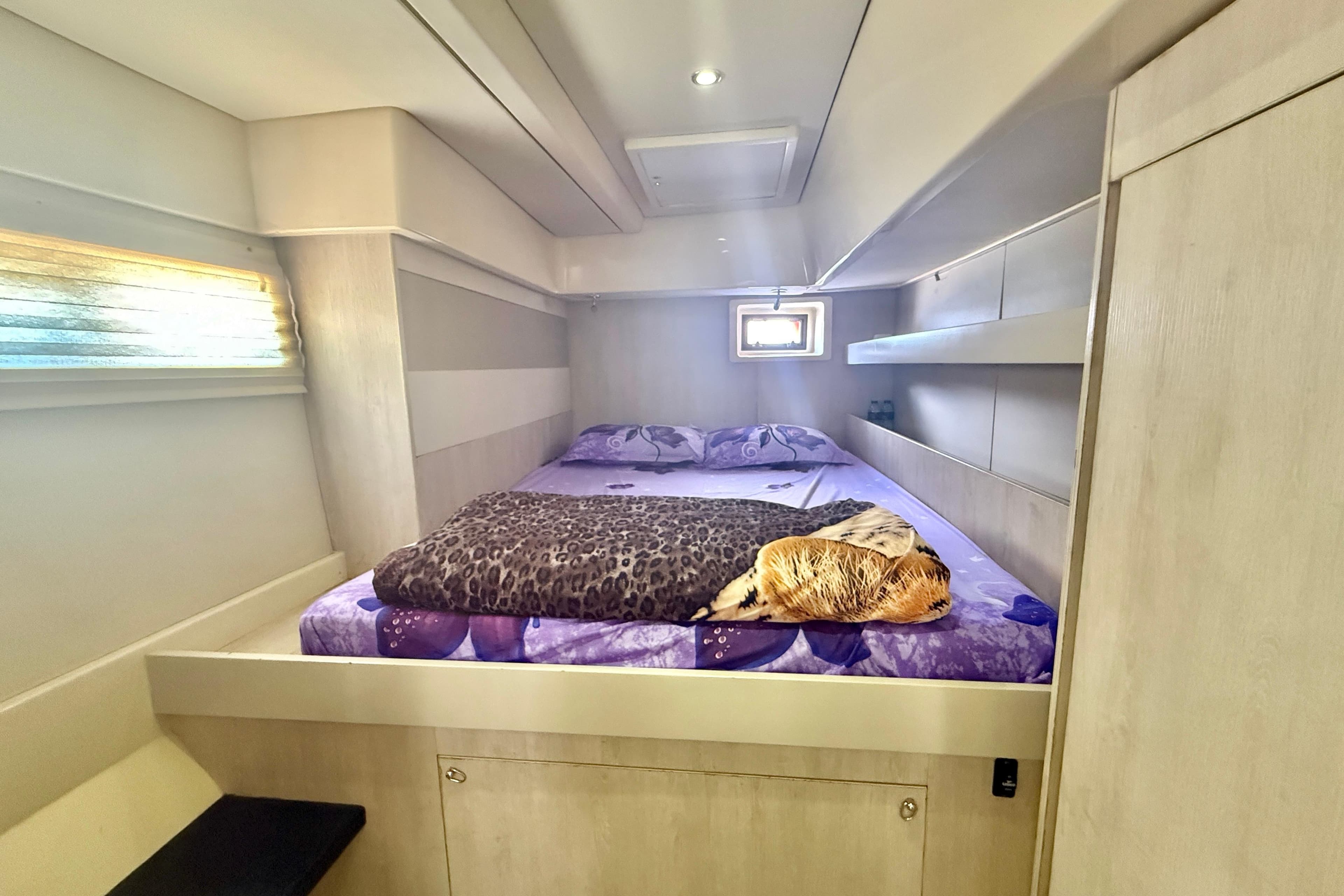Cozy bedroom interior of 2015 Leopard 51 Powercat with purple bedding and soft lighting.