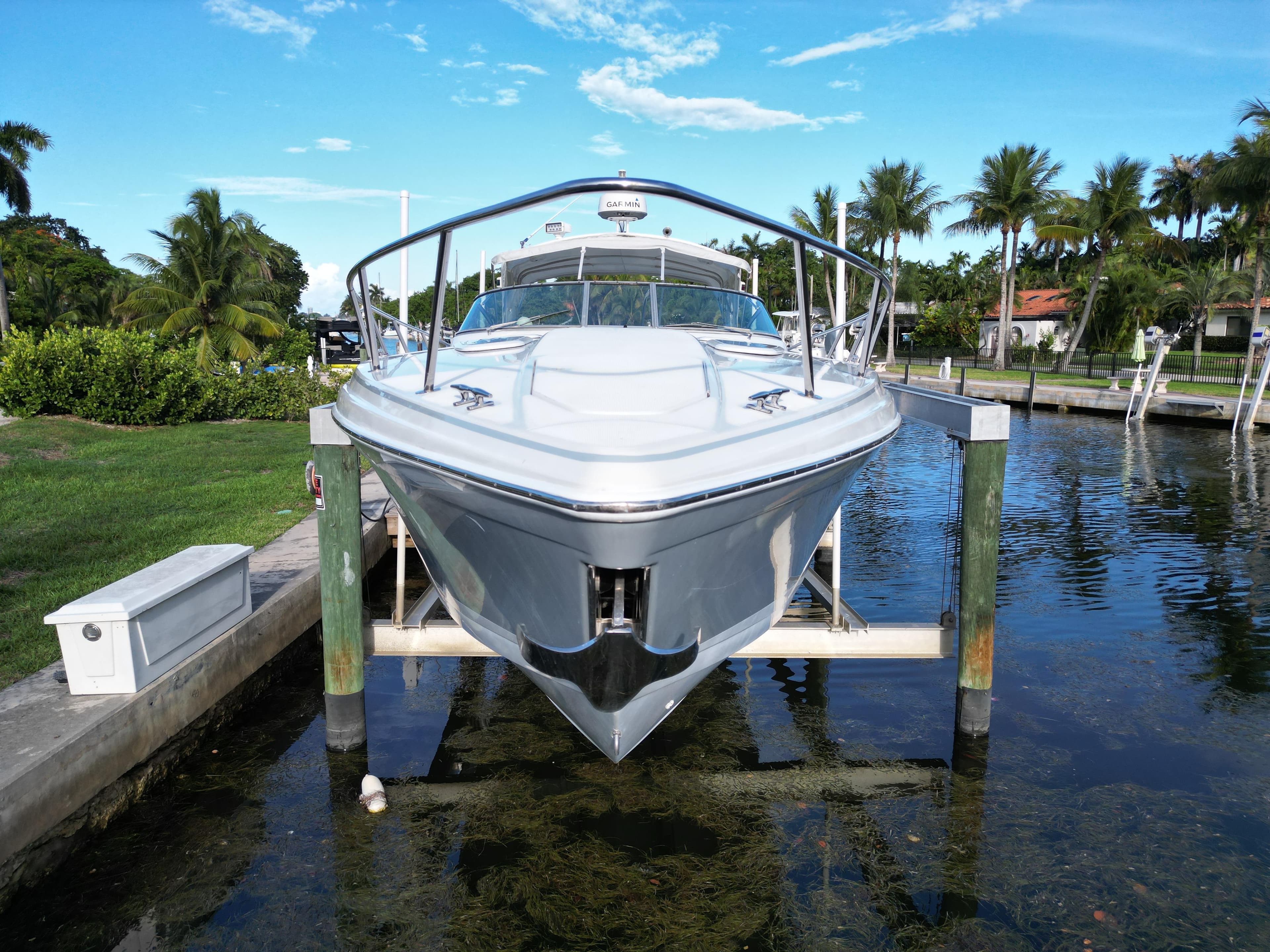 1999 Formula 400 Super Sport boat docked on a lift, surrounded by palm trees and clear skies.