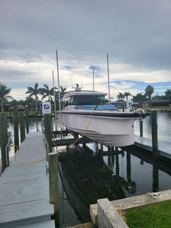 2024 Axopar 37 XC CROSS CABIN boat docked at marina with palm trees.