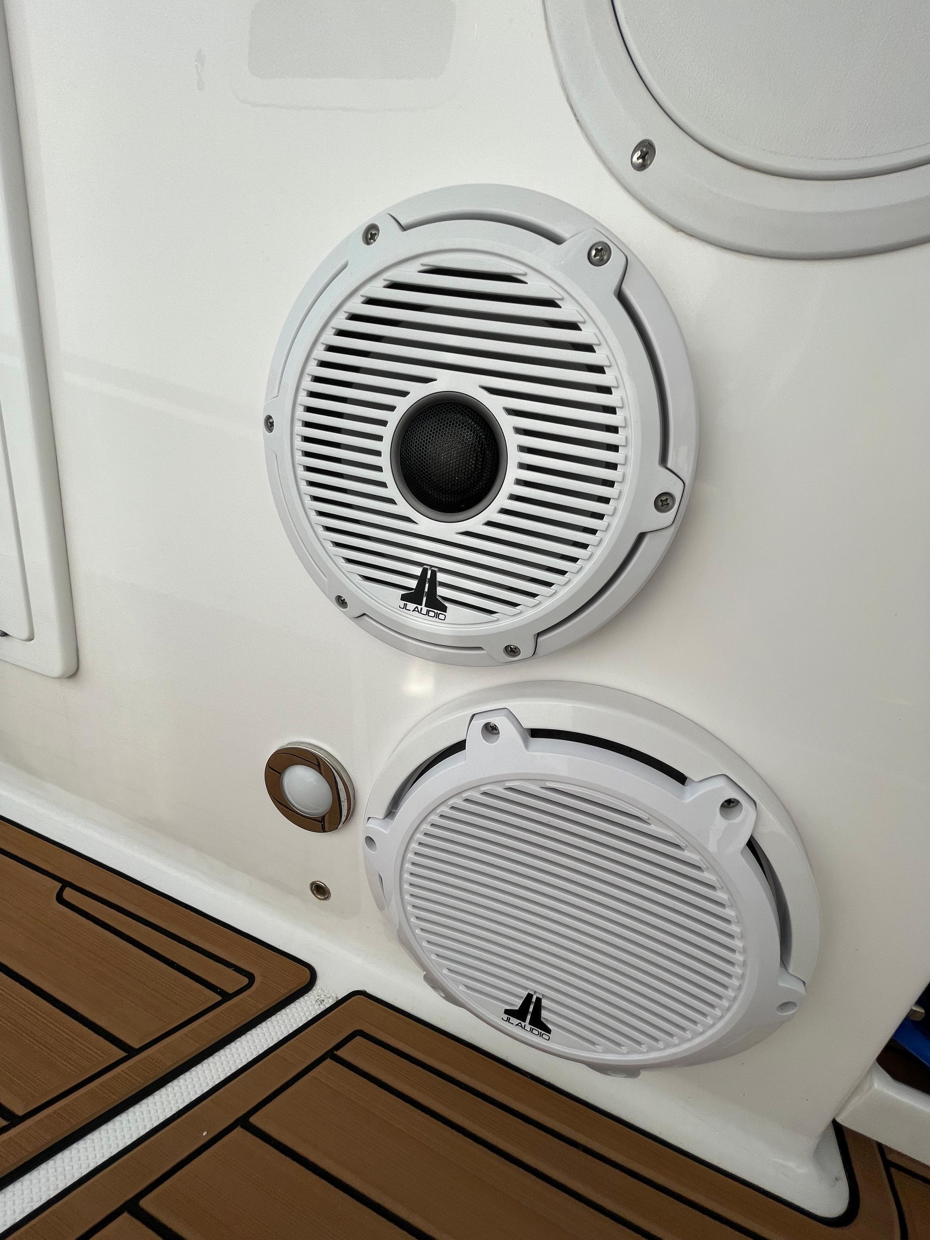 Speakers on 2019 Everglades 435 CC boat, featuring sleek white design and wood-patterned flooring.