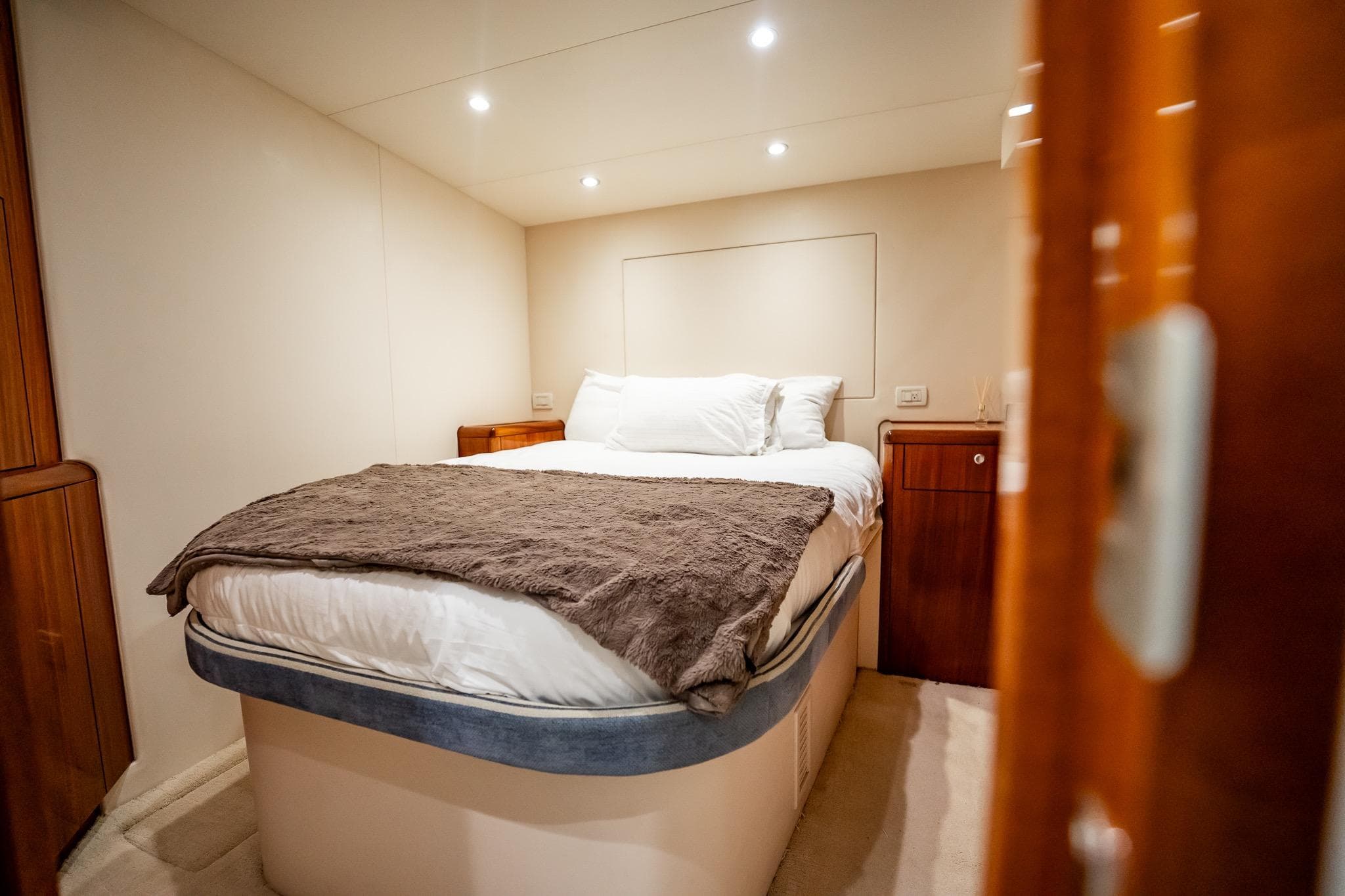 Luxurious bedroom interior of 2012 Hatteras 80 Motor Yacht with cozy bedding.