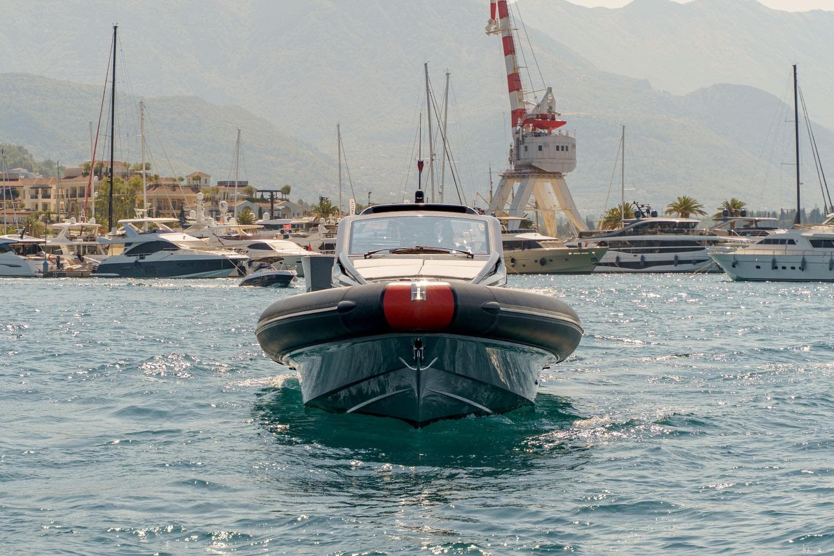 2023 Anvera 48 yacht in a bustling marina with scenic mountain backdrop.