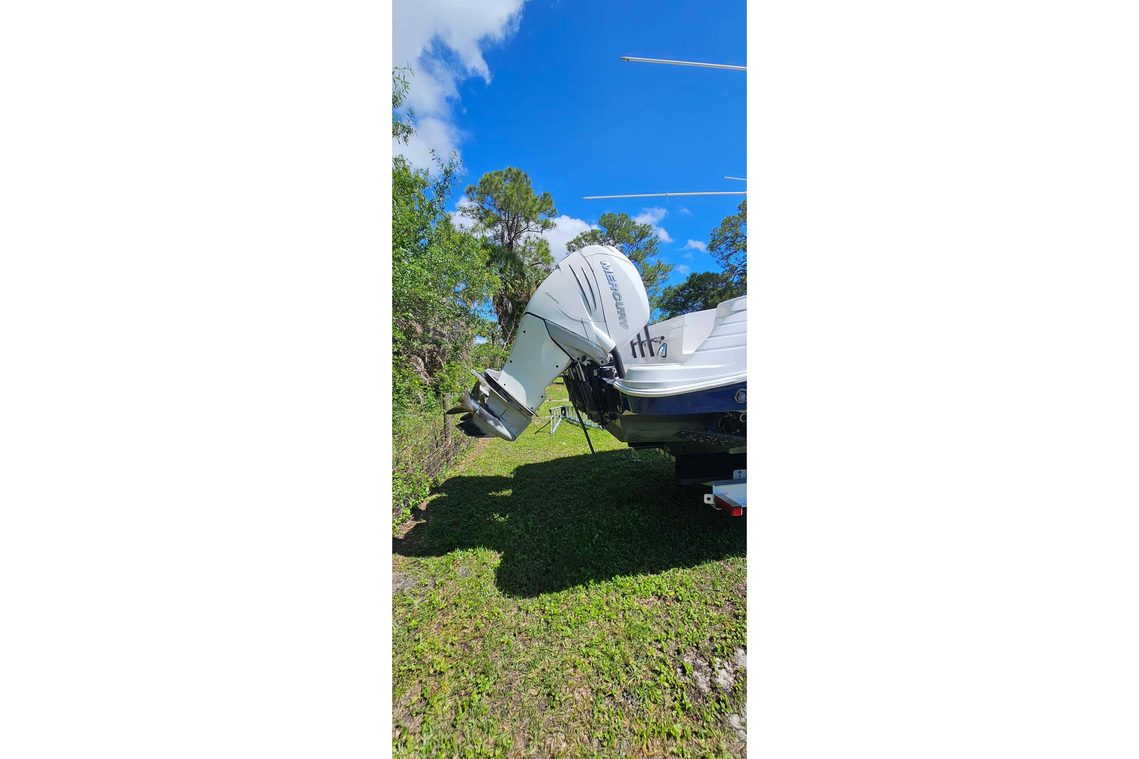 2004 Donzi 38 ZSF boat with Mercury outboard engine, parked on grass under blue sky.