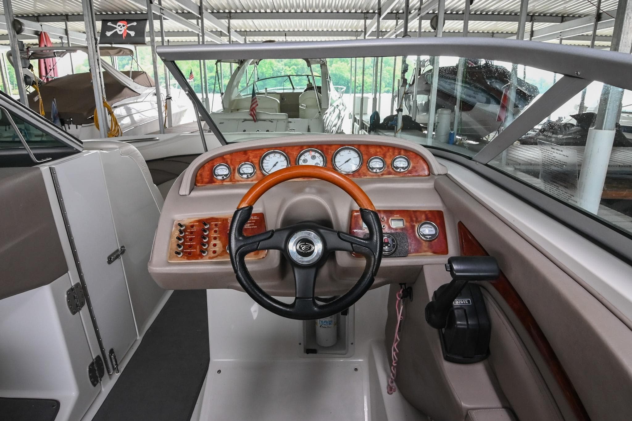 2005 Cobalt 262 boat dashboard with wooden accents and steering wheel in marina setting.