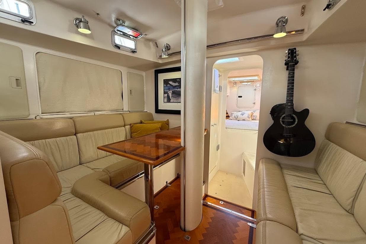 Luxurious 2011 Reliance 44 yacht interior with leather seating, wooden table, and mounted guitar.