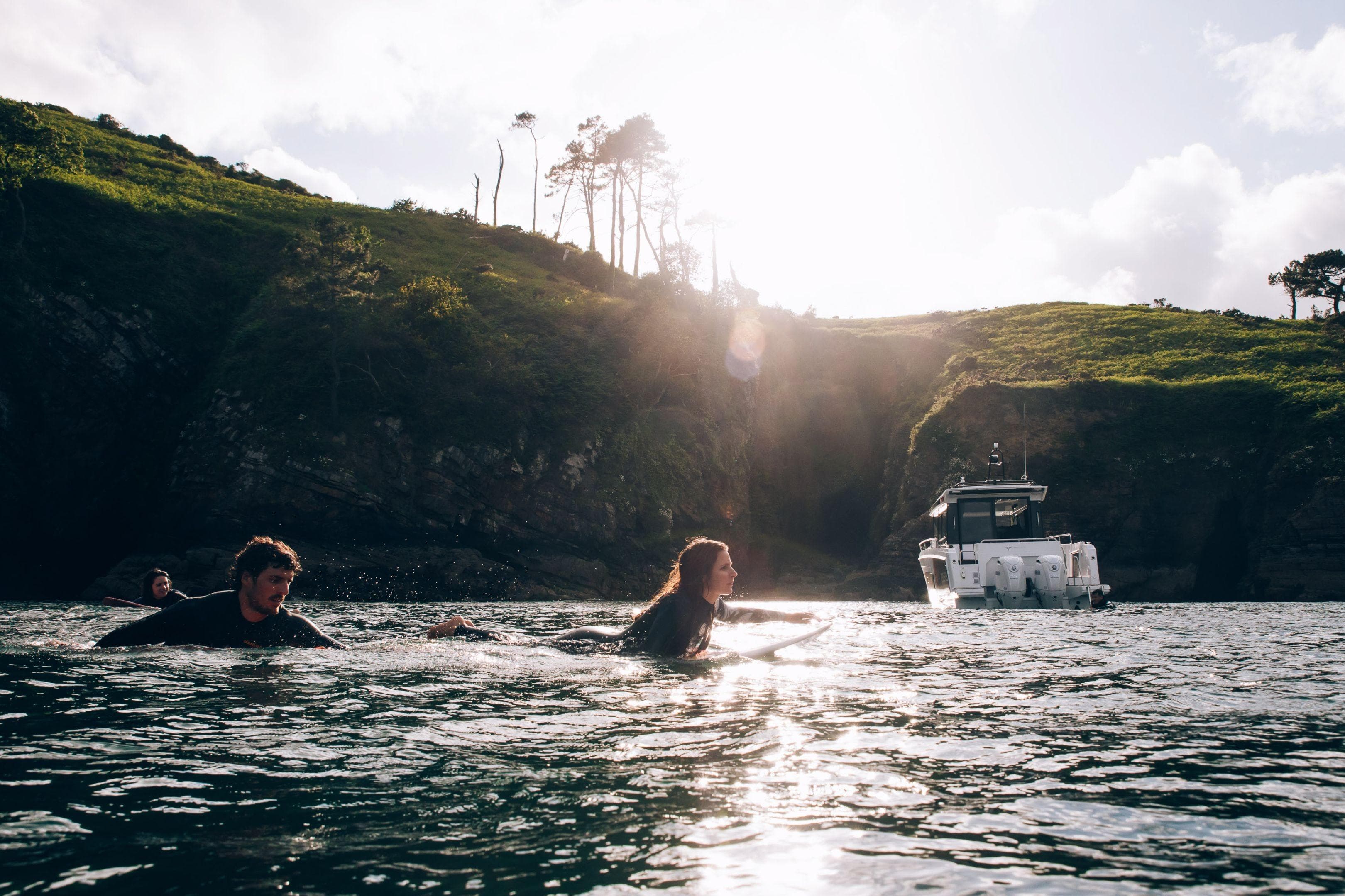 People swimming near Jeanneau NC 895 Sport Series 2 boat, 2026 model, in scenic coastal waters.