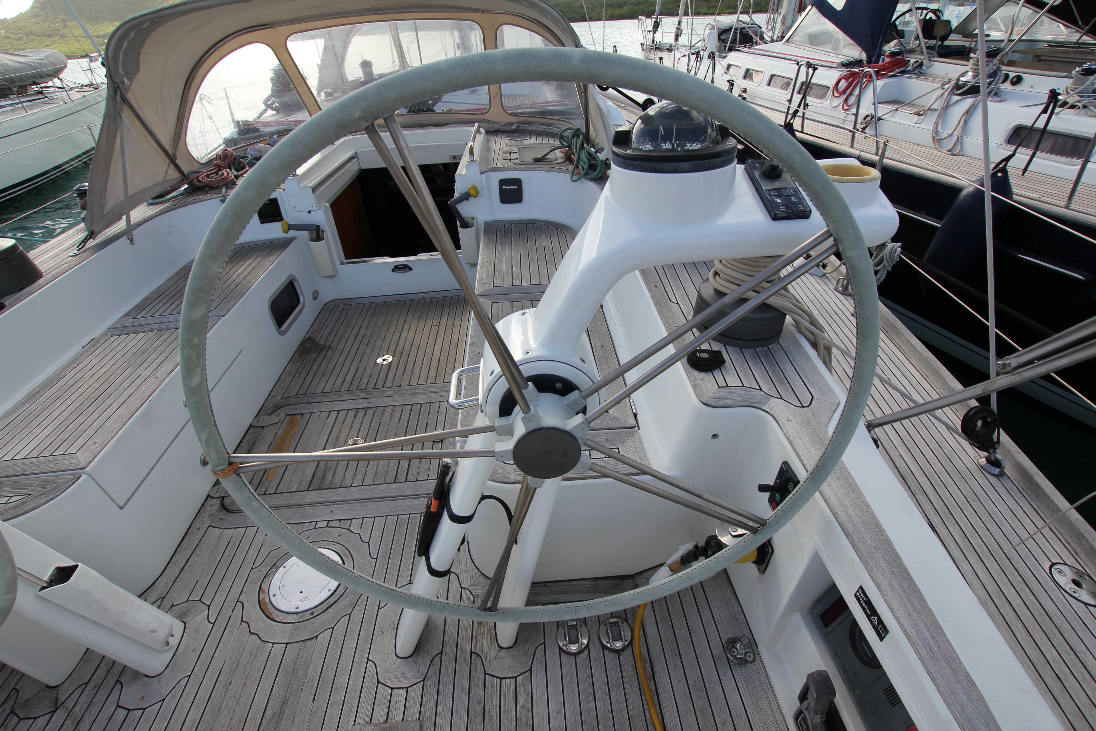 Cockpit of a 2006 Baltic 56 sailboat with a large steering wheel and teak decking.