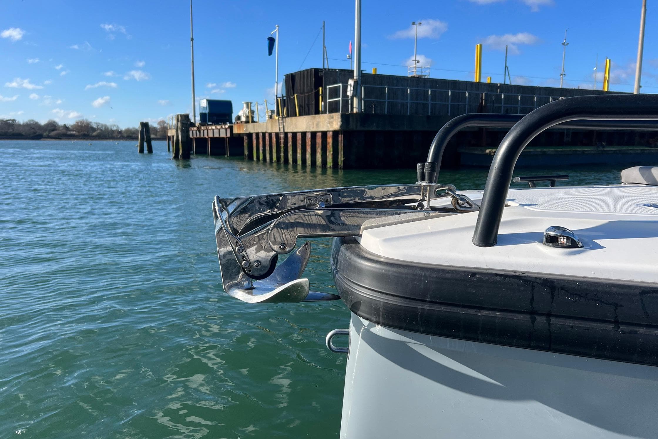 2019 Axopar 28 T-Top boat with anchor, docked by a pier on a sunny day.