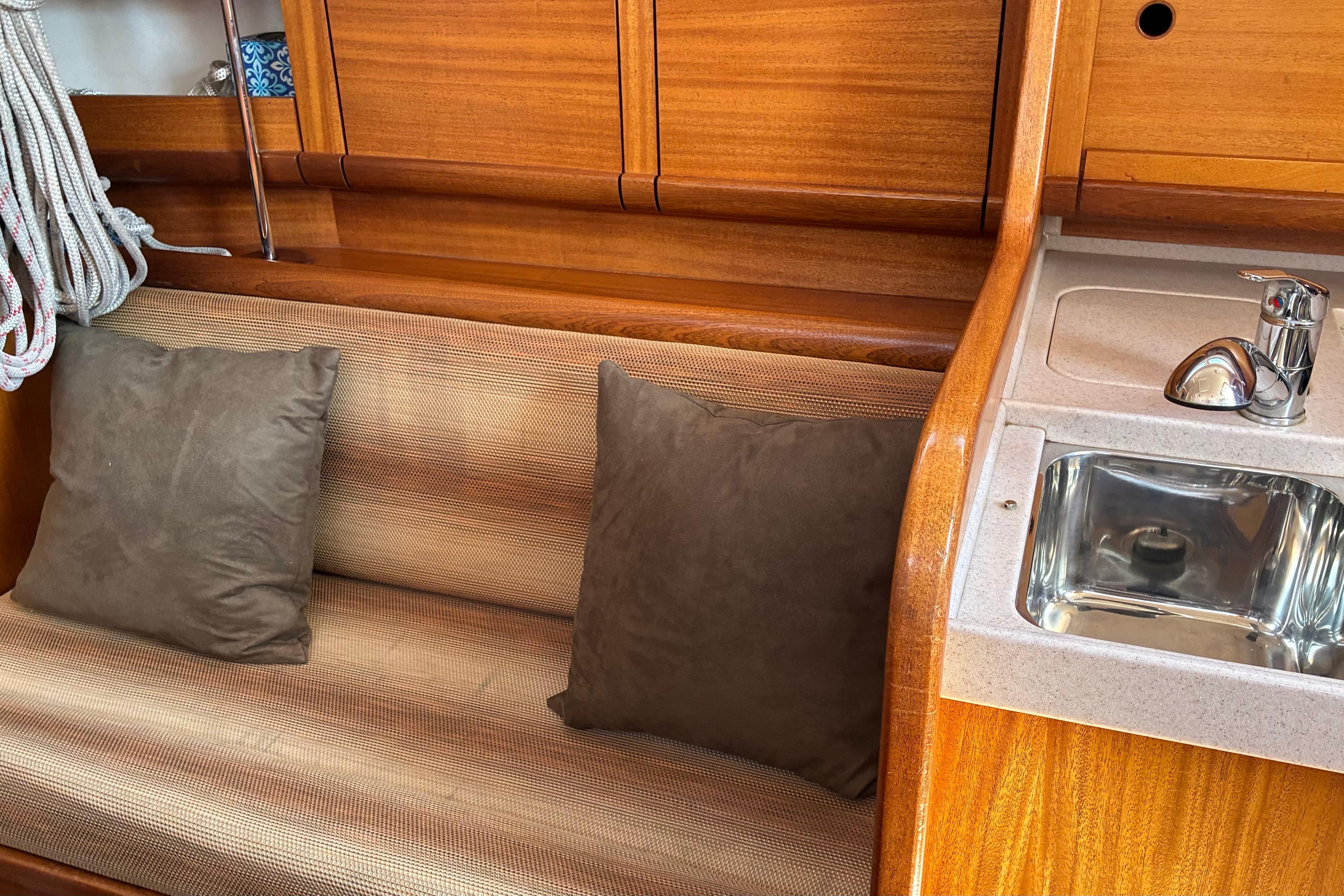Interior of 2007 Delphia 33 yacht with wooden finish, cushioned seating, and compact sink.