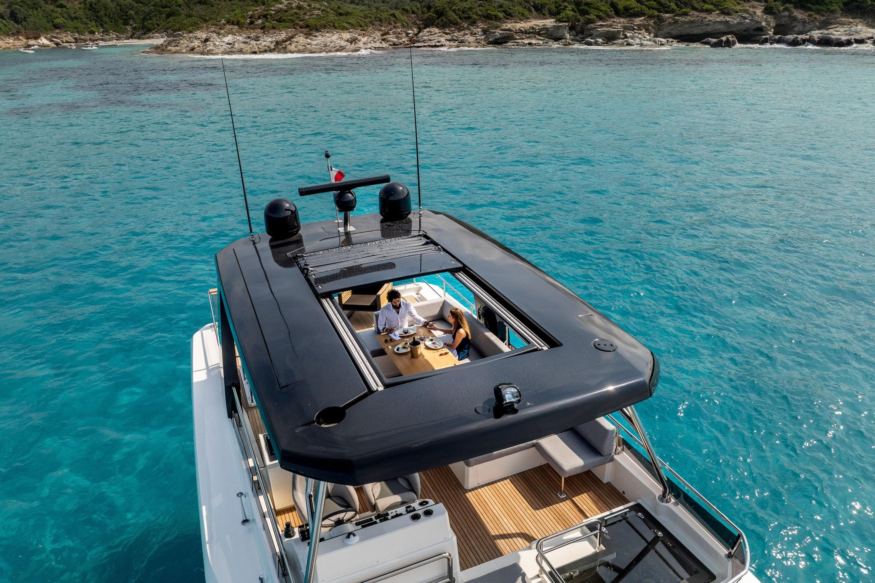 Beneteau Grand Trawler 63 (2025) cruising in clear blue waters, top deck view.