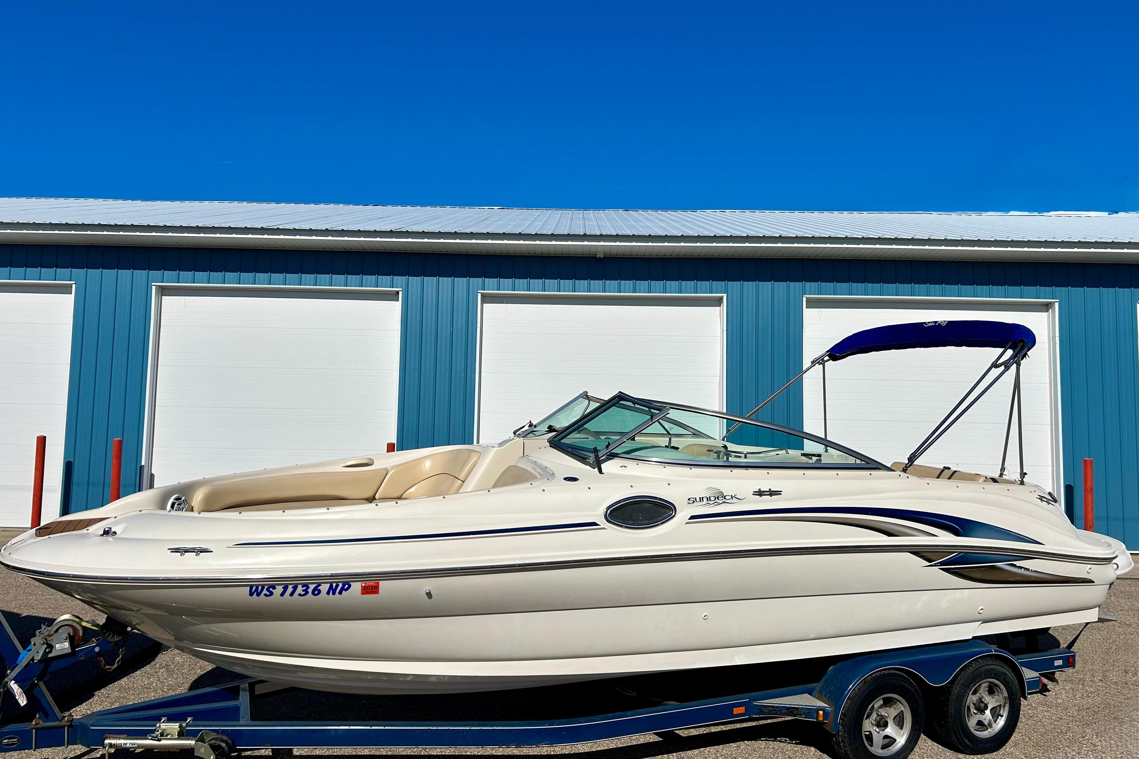2000 Sea Ray 240 Sundeck boat on trailer, parked in front of blue storage units.