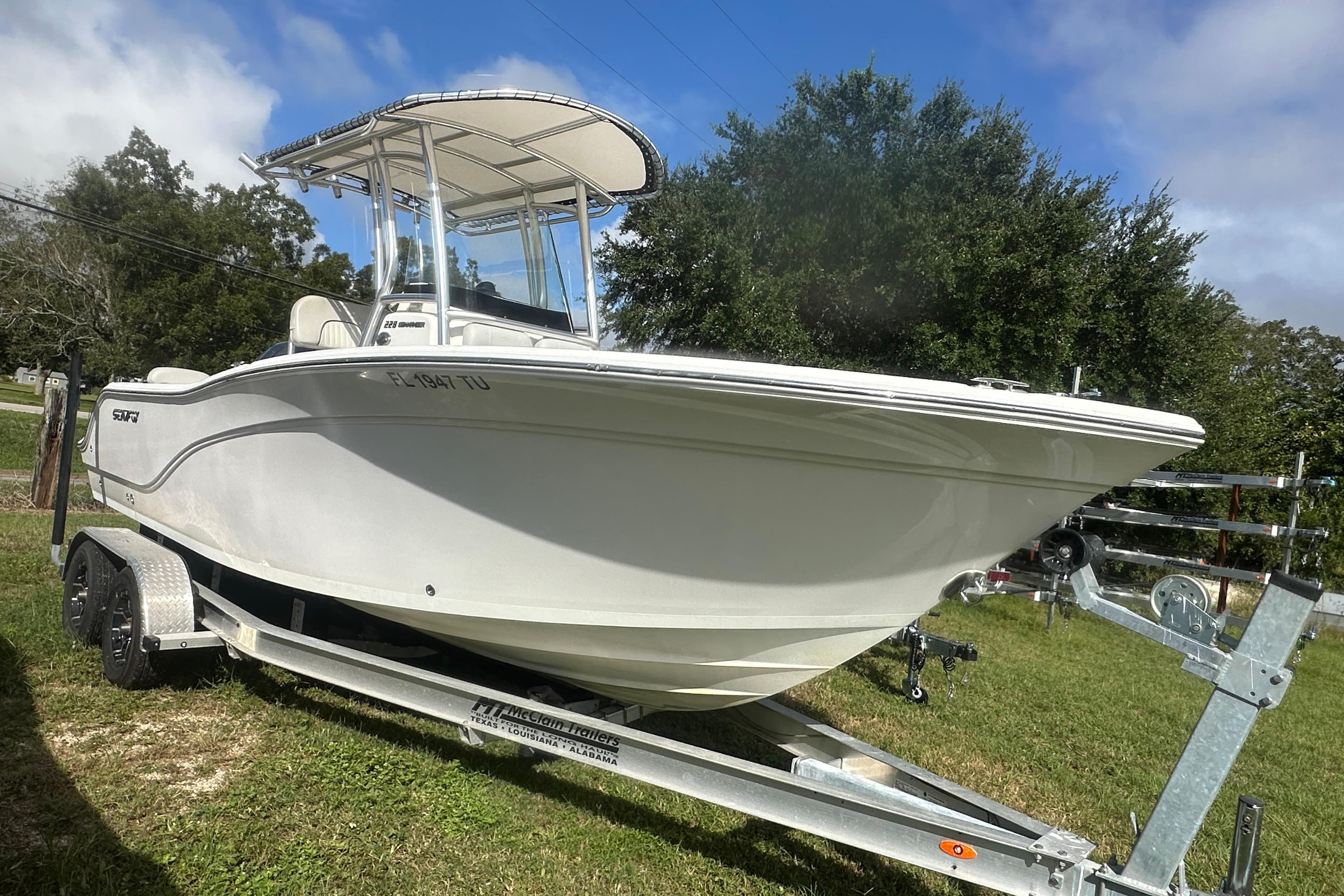 2023 Sea Fox 228 Commander boat on trailer, parked on grass under blue sky.