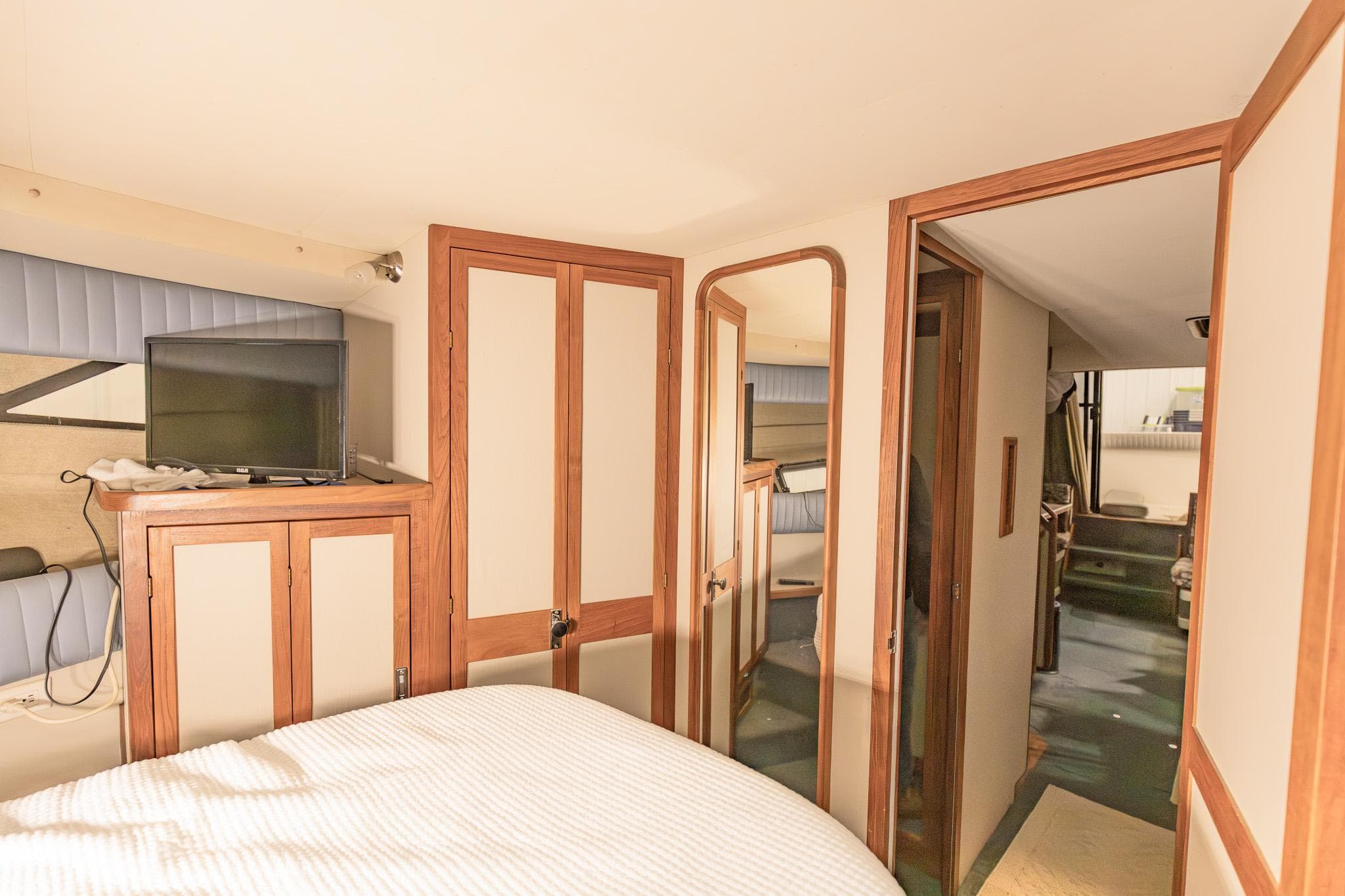 Interior of 1987 Carver 3697 Mariner yacht, featuring cozy bedroom and wooden cabinetry.