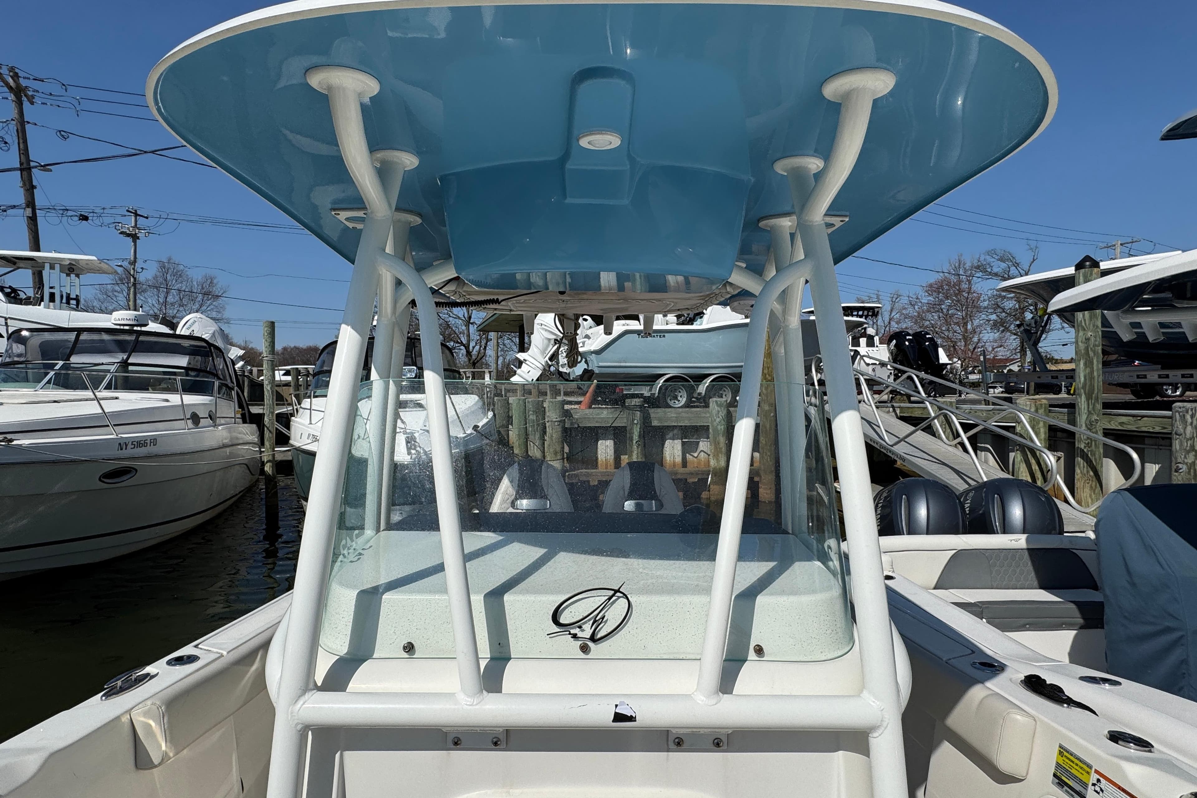 2022 Sailfish 242 CC boat with blue T-top, docked among other boats.