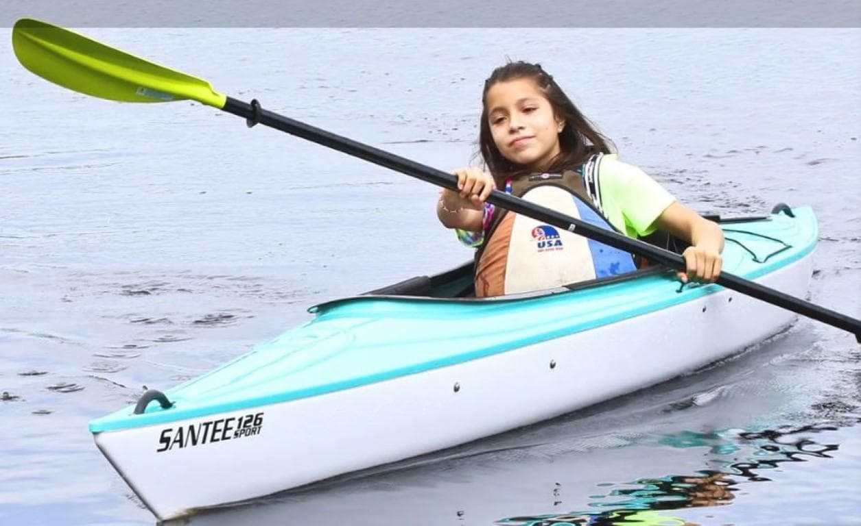 Young girl kayaking in a 2023 Hurricane Kayaks Santee 126 Sport on calm water.