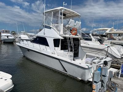1989 Trojan 12 Meter Convertible yacht docked at marina under blue sky.