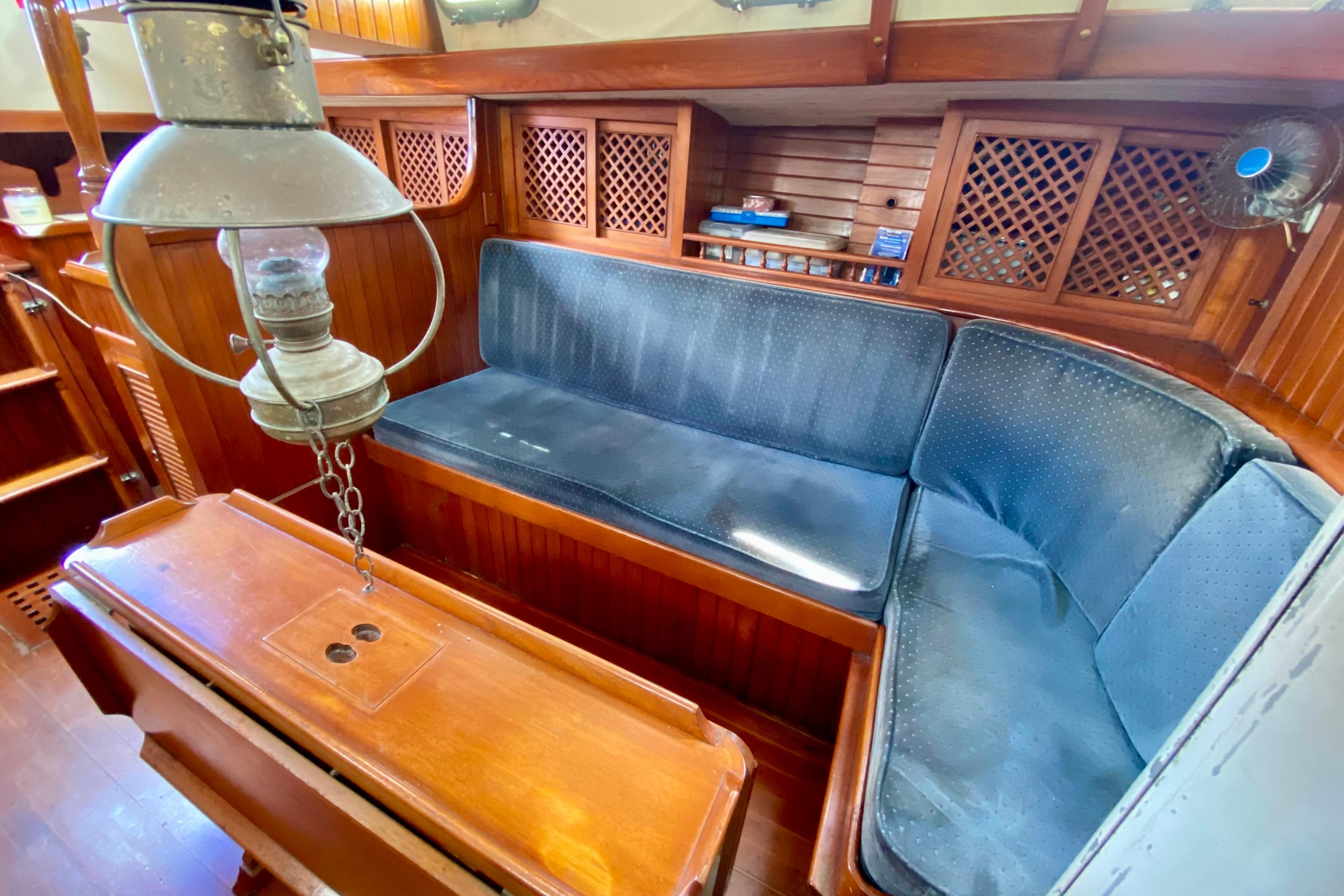 Interior of 1981 Union EO 32 sailboat with wooden seating and vintage lamp.