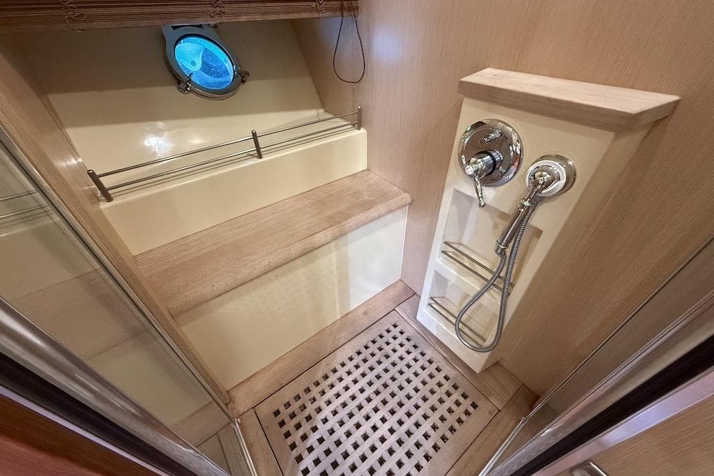 Luxurious shower area in 2008 Mochi Craft 64' Dolphin yacht with wooden accents and porthole.