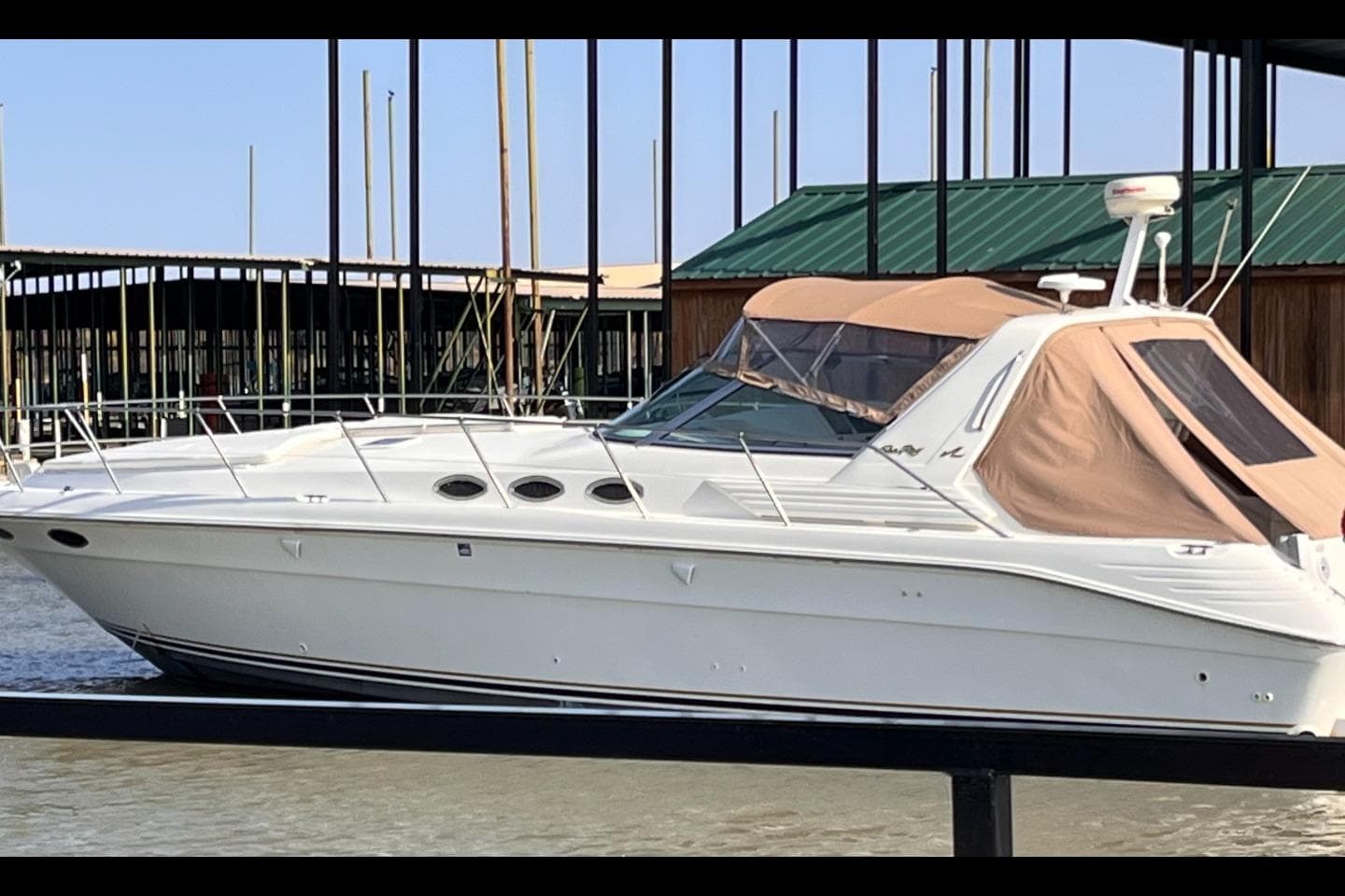 1996 Sea Ray 400 Express Cruiser docked at marina, featuring sleek white design and tan canopy.