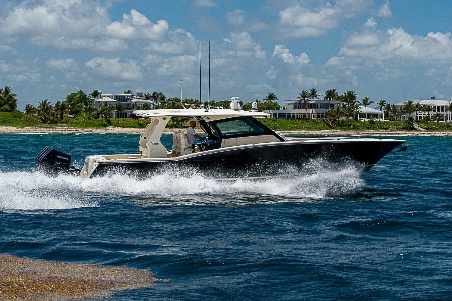 2025 Scout 425 LXF boat cruising on blue ocean near tropical shoreline.
