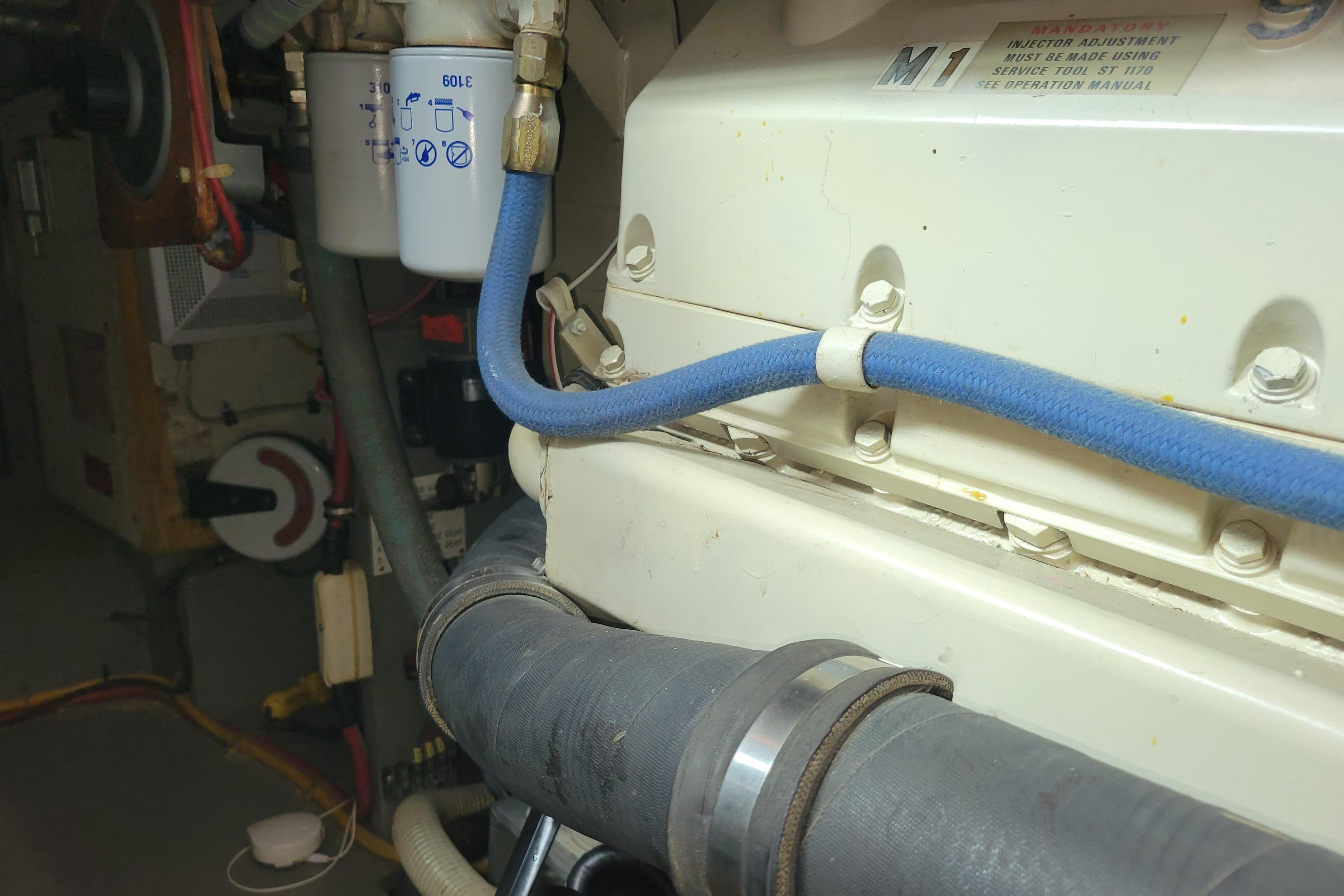 Engine room of 1977 Hatteras 43 Double Cabin with visible hoses and filter.